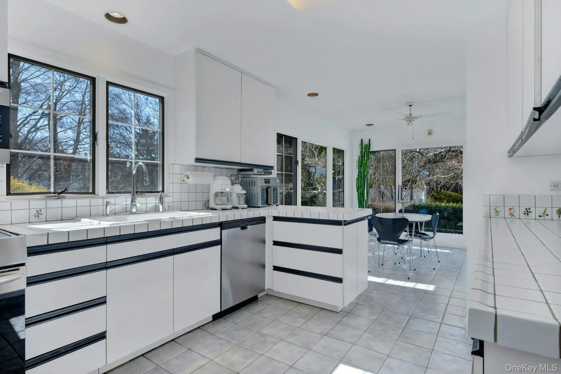 Kitchen with island and ample storage and above island cabinetry flanking dining areas for convenient serving Kitchen with island and ample storage and above island cabinetry flanking dining areas for convenient serving