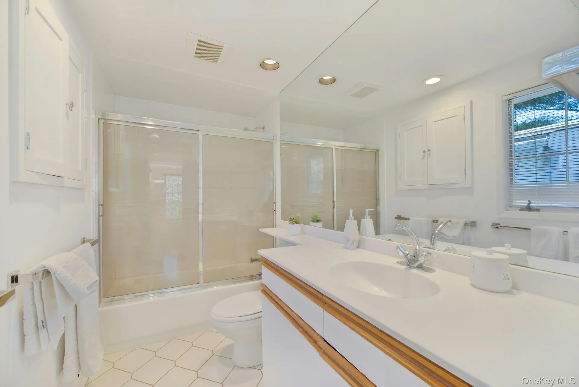 Full bedroom with bathtub, shower & recessed lighting, vanity, visible vents, and combined bath/shower with glass door Full bedroom with bathtub, shower & recessed lighting, vanity, visible vents, and combined bath/shower with glass door