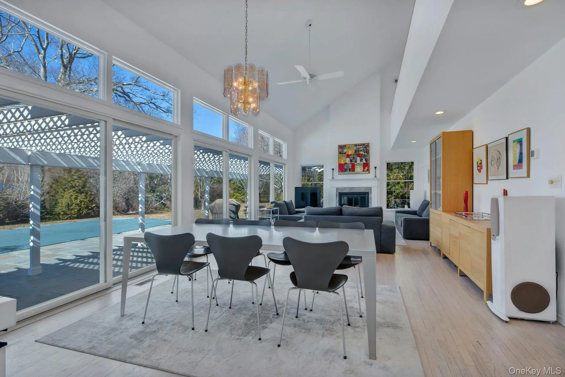 Dining room with high vaulted ceiling, light wood finished floors, a glass covered fireplace, and a healthy amount of sunlight Dining room with high vaulted ceiling, light wood finished floors, a glass covered fireplace, and a healthy amount of sunlight