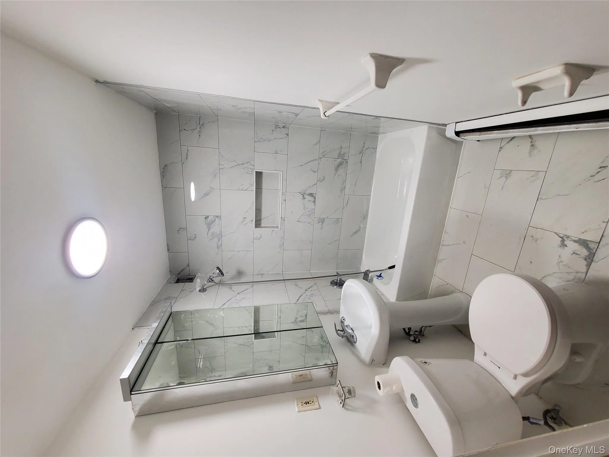 Full bathroom featuring shower / bath combination, light marble finish floors, and baseboard heating Full bathroom featuring shower / bath combination, light marble finish floors, and baseboard heating