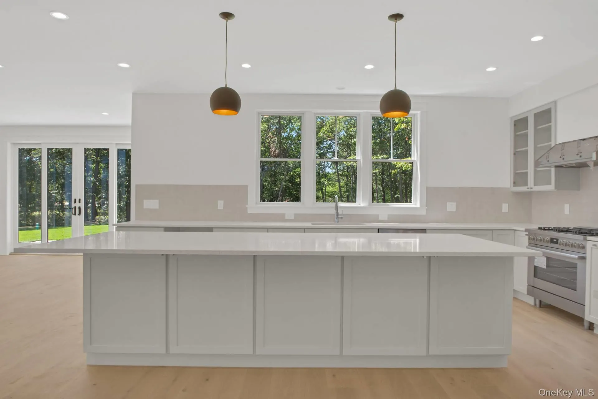 Kitchen featuring hanging light fixtures, a kitchen island, glass insert cabinets, gas stove, and recessed lighting Kitchen featuring hanging light fixtures, a kitchen island, glass insert cabinets, gas stove, and recessed lighting