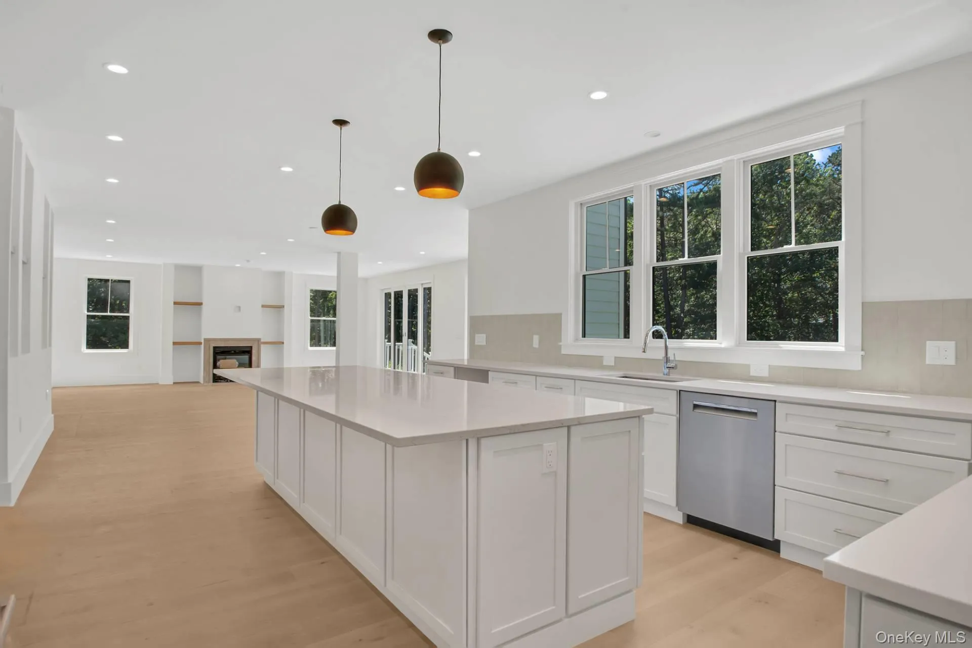 Kitchen featuring white cabinets, hanging light fixtures, stainless steel dishwasher, recessed lighting, and light wood-style floors Kitchen featuring white cabinets, hanging light fixtures, stainless steel dishwasher, recessed lighting, and light wood-style floors