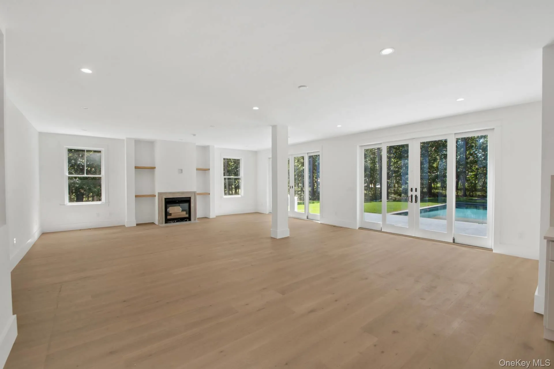 Unfurnished living room with light wood-type flooring, french doors, recessed lighting, and a fireplace Unfurnished living room with light wood-type flooring, french doors, recessed lighting, and a fireplace