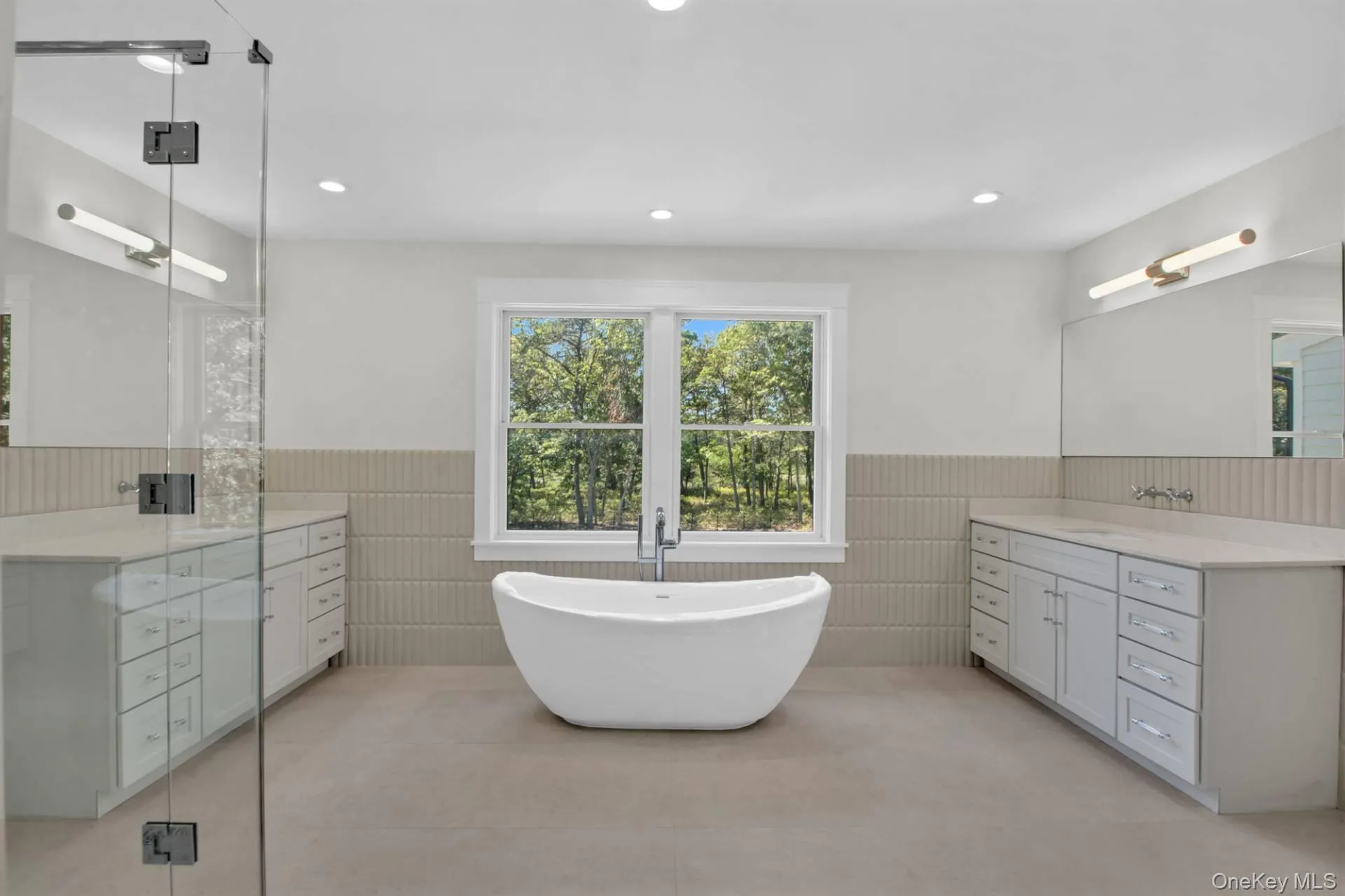Bathroom with wainscoting, vanity, a freestanding tub, light tile patterned floors, and recessed lighting Bathroom with wainscoting, vanity, a freestanding tub, light tile patterned floors, and recessed lighting