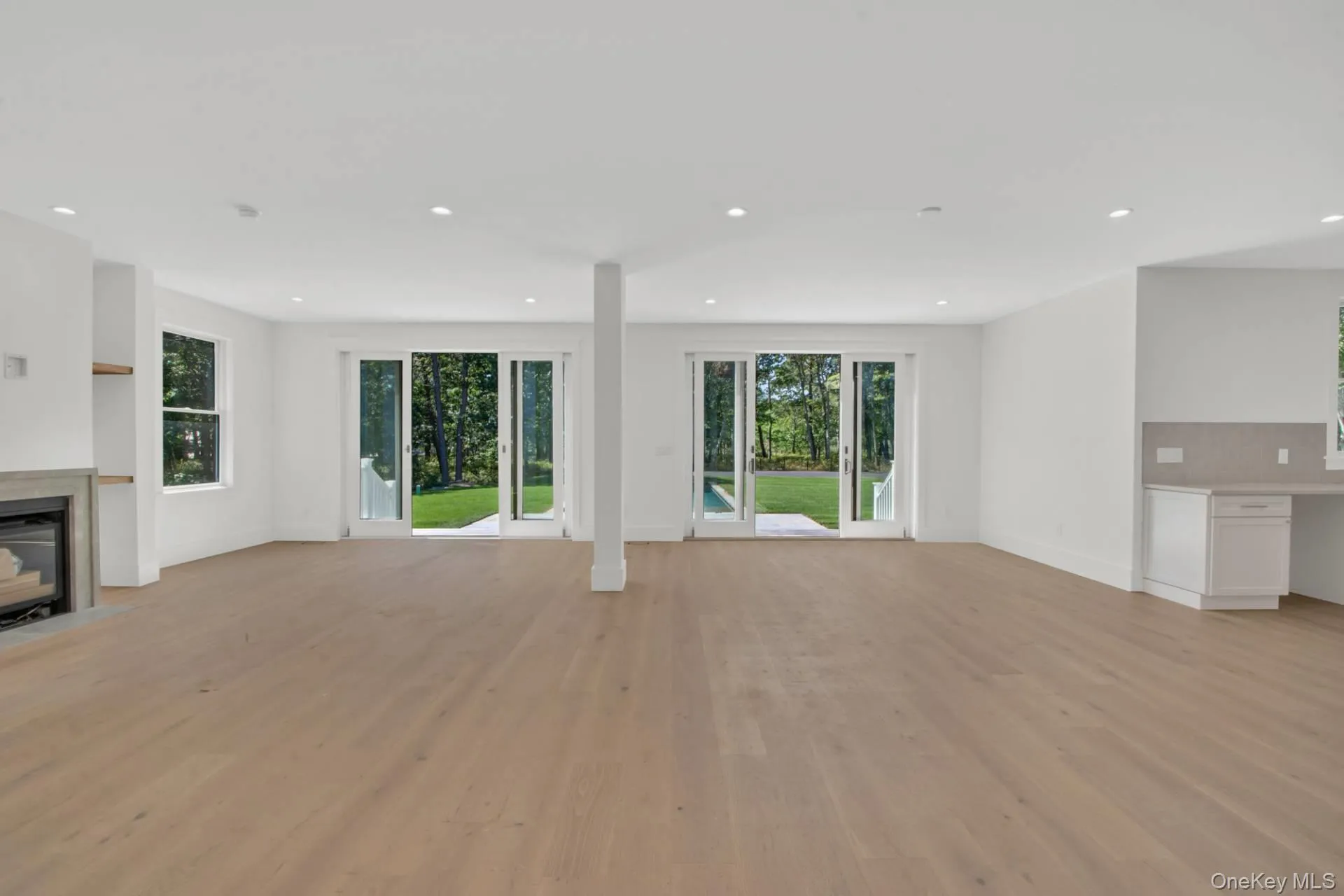 Unfurnished living room featuring healthy amount of natural light, light wood-style flooring, recessed lighting, and a fireplace Unfurnished living room featuring healthy amount of natural light, light wood-style flooring, recessed lighting, and a fireplace