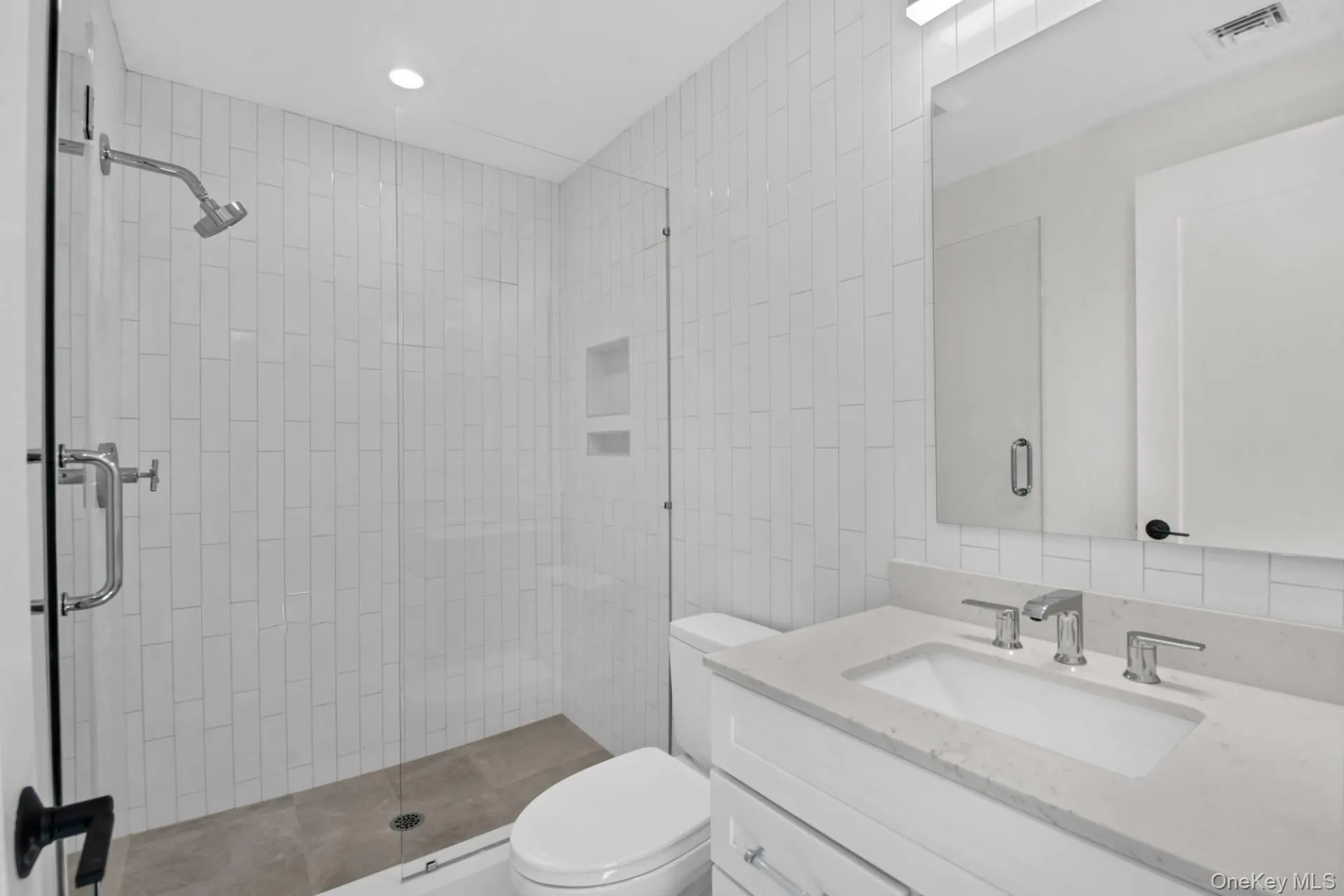 Bathroom with a stall shower, vanity, tile walls, and recessed lighting Bathroom with a stall shower, vanity, tile walls, and recessed lighting