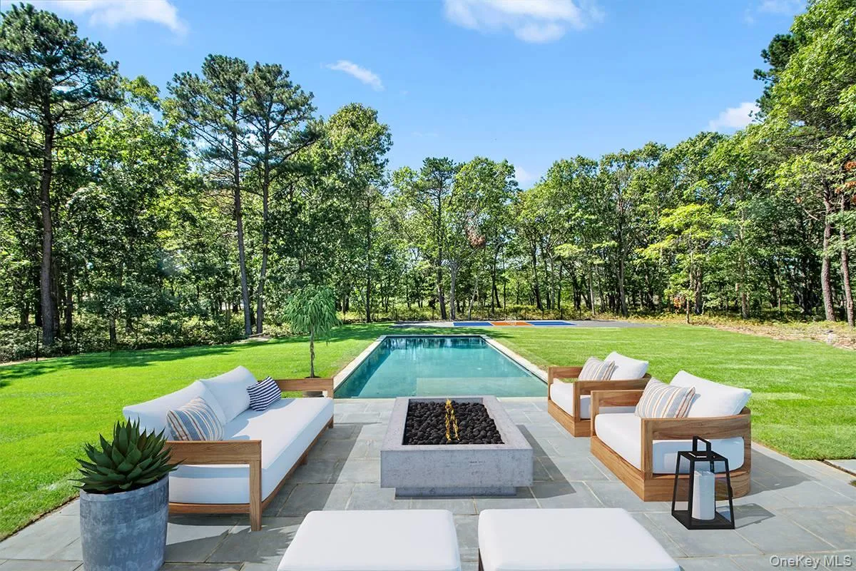 View of swimming pool featuring an outdoor living space with a fire pit, a lawn, a patio area, and view of scattered trees View of swimming pool featuring an outdoor living space with a fire pit, a lawn, a patio area, and view of scattered trees