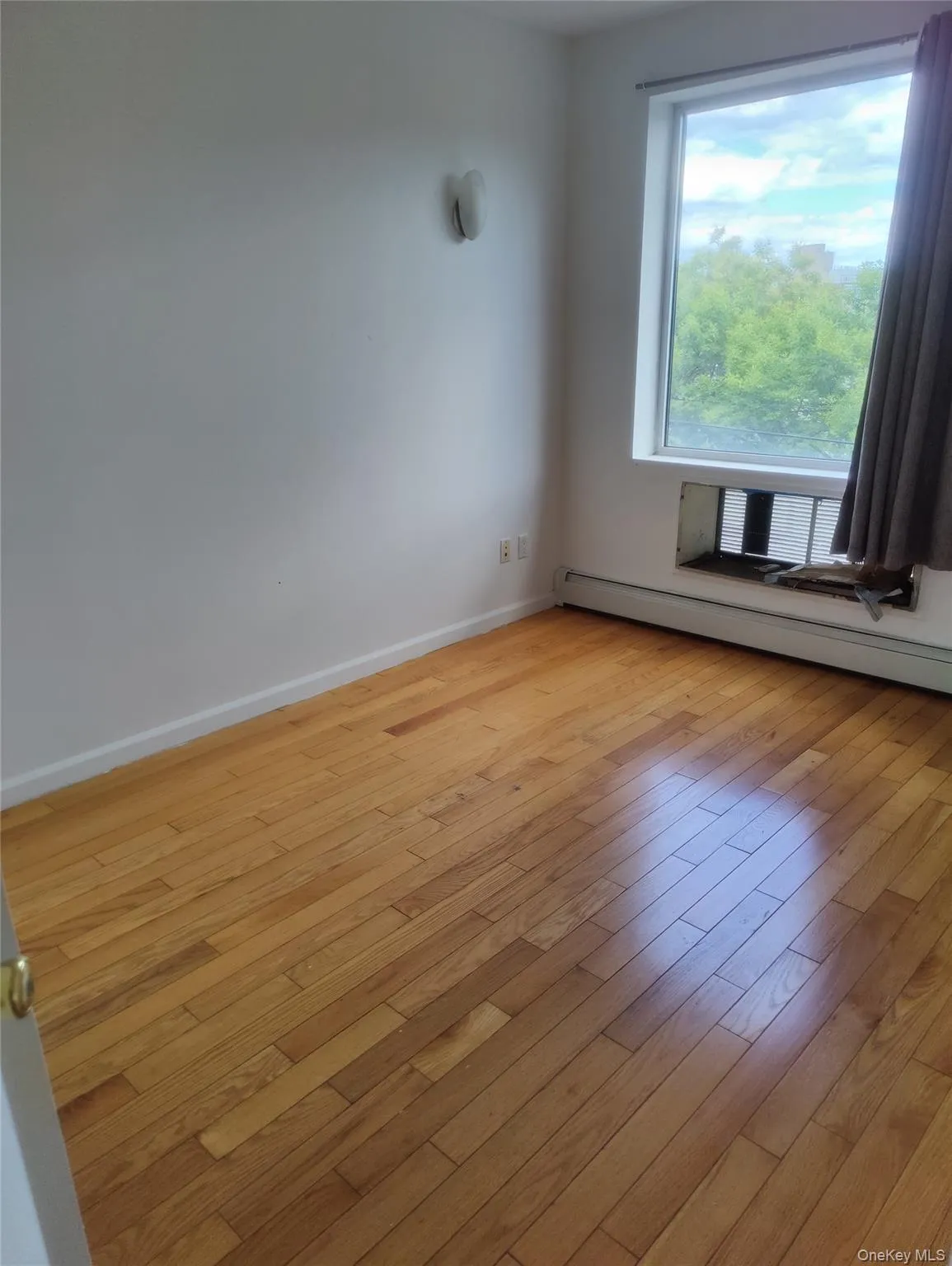 Empty room with baseboard heating and light wood-style floors Empty room with baseboard heating and light wood-style floors