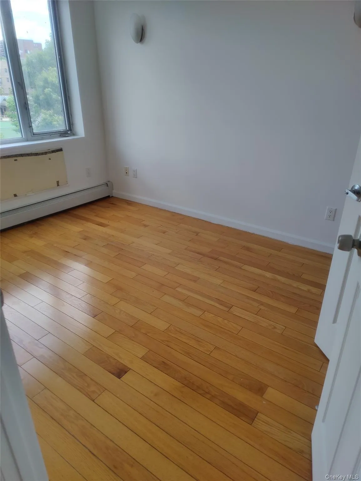 Unfurnished room featuring baseboard heating and light wood-style floors Unfurnished room featuring baseboard heating and light wood-style floors
