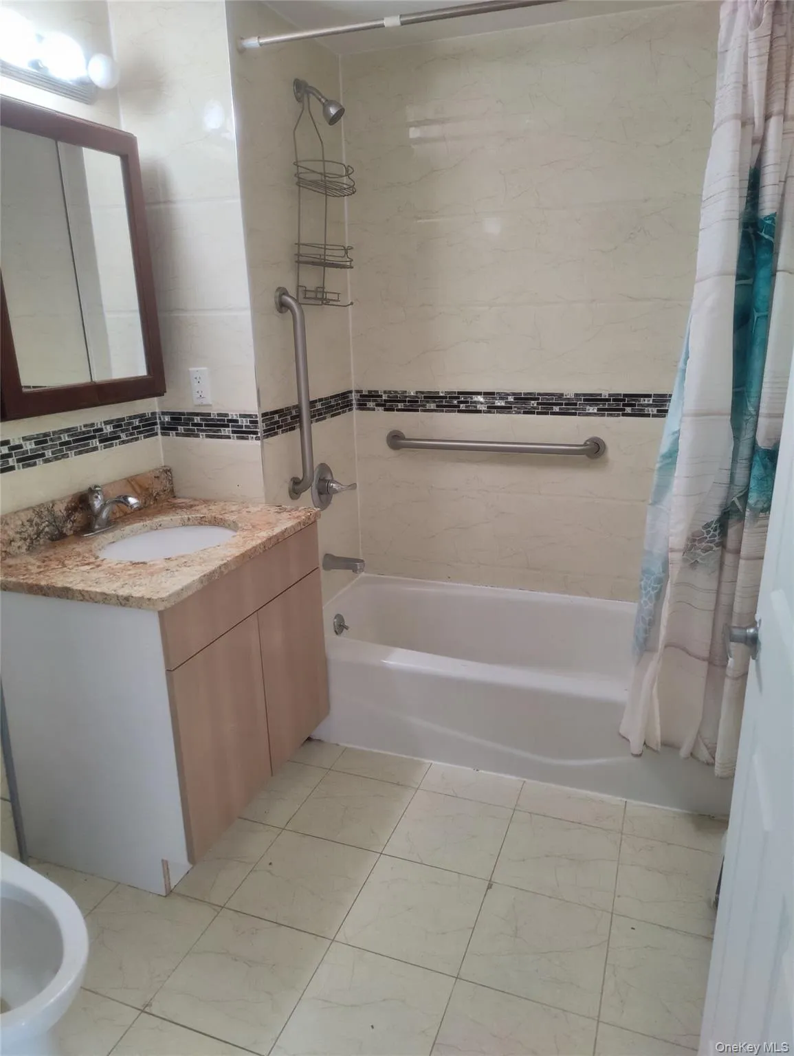 Bathroom featuring shower / bath combination with curtain, vanity, a bidet, tile walls, and light tile patterned floors Bathroom featuring shower / bath combination with curtain, vanity, a bidet, tile walls, and light tile patterned floors