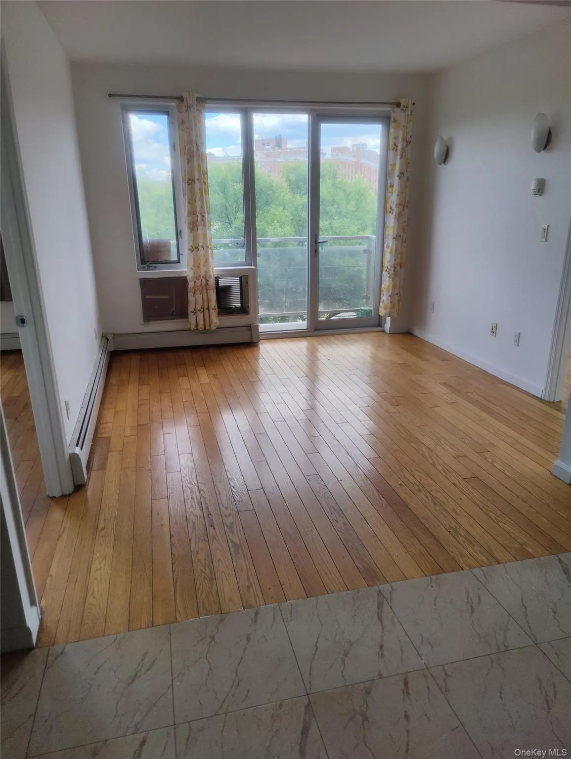 Unfurnished living room featuring a baseboard radiator and light wood-type flooring Unfurnished living room featuring a baseboard radiator and light wood-type flooring