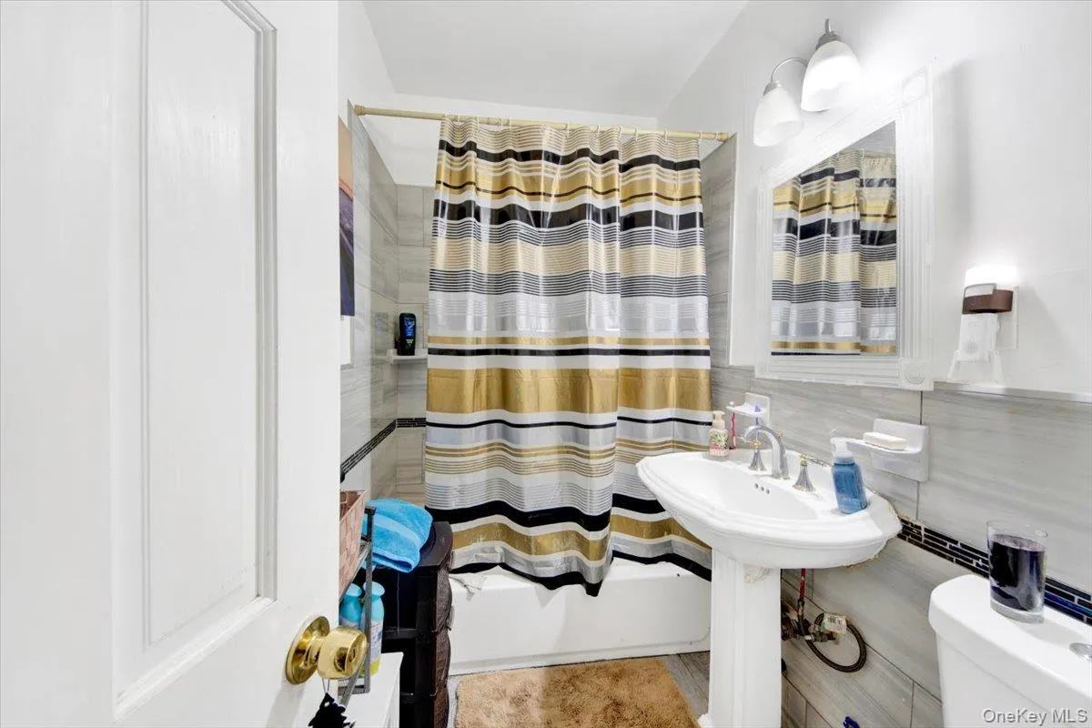 Full bathroom with tile walls and shower / bath combination with curtain Full bathroom with tile walls and shower / bath combination with curtain
