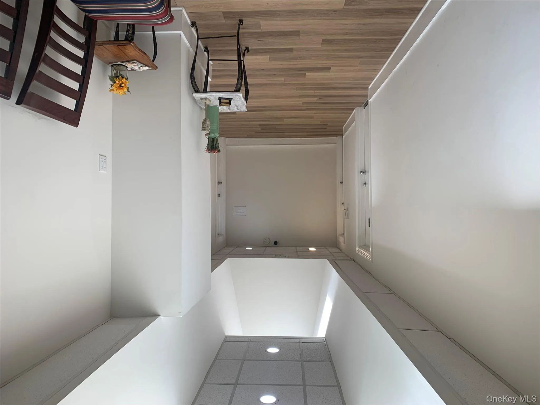 Hallway featuring recessed lighting, a drop ceiling, light wood-style floors, and a towering ceiling Hallway featuring recessed lighting, a drop ceiling, light wood-style floors, and a towering ceiling