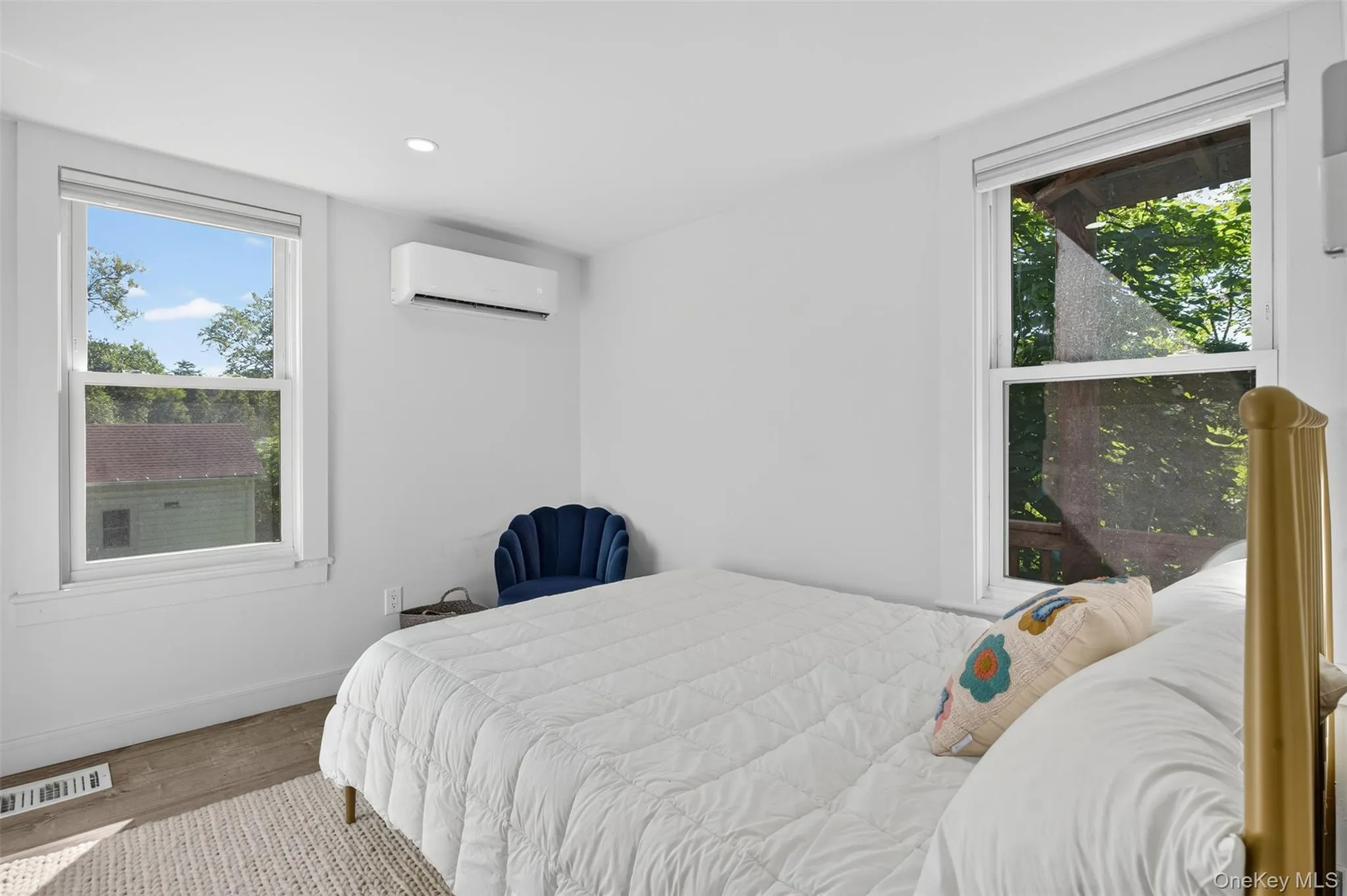 Bedroom featuring wood finished floors, multiple windows, recessed lighting, and a wall mounted AC Bedroom featuring wood finished floors, multiple windows, recessed lighting, and a wall mounted AC