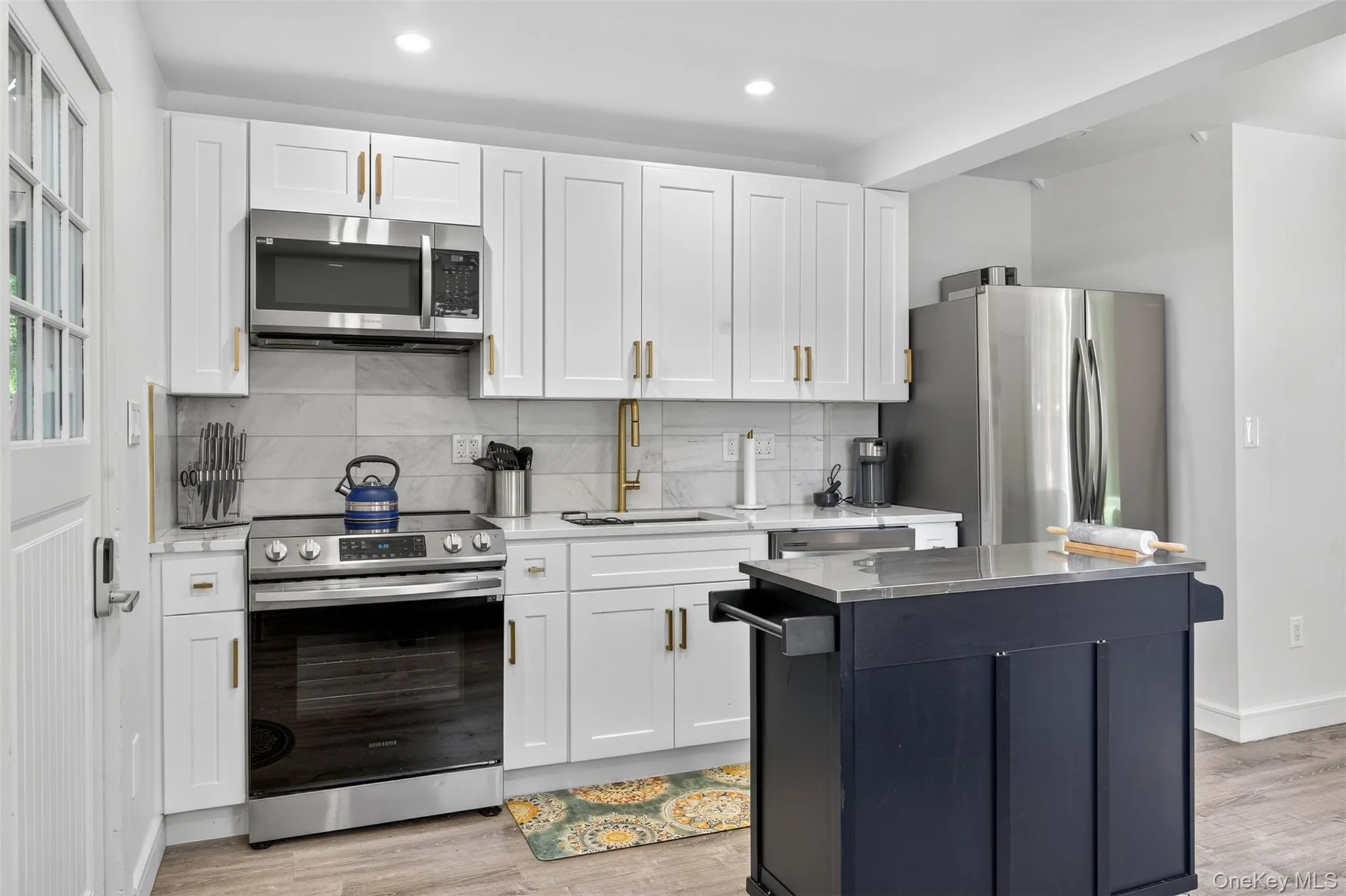 Kitchen featuring stainless steel appliances, stone countertops, island and clean, modern finishes Kitchen featuring stainless steel appliances, stone countertops, island and clean, modern finishes