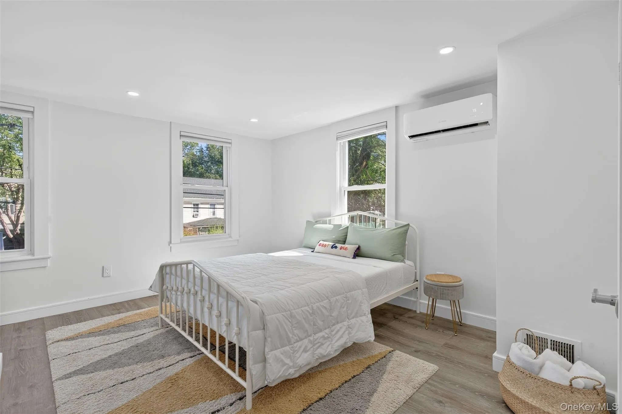Bedroom featuring recessed lighting, multiple windows, light wood-style flooring, and a wall mounted AC Bedroom featuring recessed lighting, multiple windows, light wood-style flooring, and a wall mounted AC