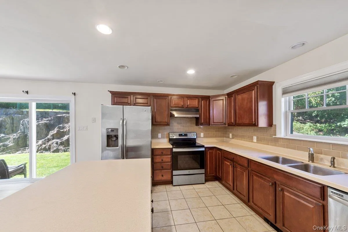 Kitchen featuring stainless steel appliances, recessed lighting, tasteful backsplash, light countertops, and light tile patterned flooring Kitchen featuring stainless steel appliances, recessed lighting, tasteful backsplash, light countertops, and light tile patterned flooring