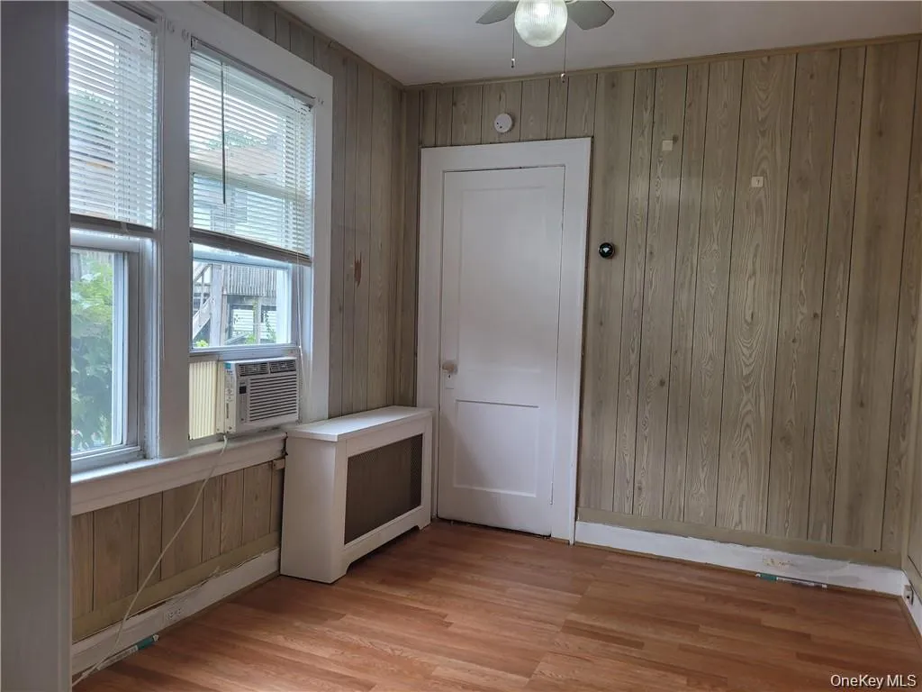 Doorway with wooden walls, wood finished floors, radiator, and a ceiling fan Doorway with wooden walls, wood finished floors, radiator, and a ceiling fan