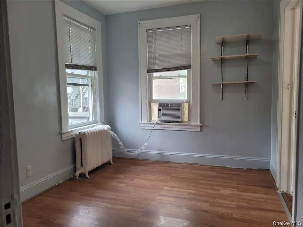 Empty room featuring radiator and wood finished floors Empty room featuring radiator and wood finished floors