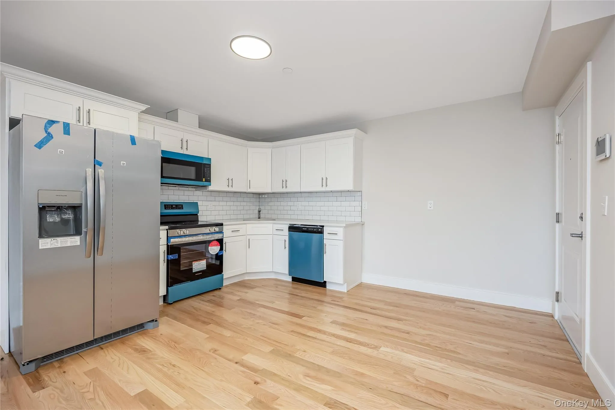 Kitchen with appliances with stainless steel finishes, tasteful backsplash, light wood-style flooring, and white cabinetry Kitchen with appliances with stainless steel finishes, tasteful backsplash, light wood-style flooring, and white cabinetry