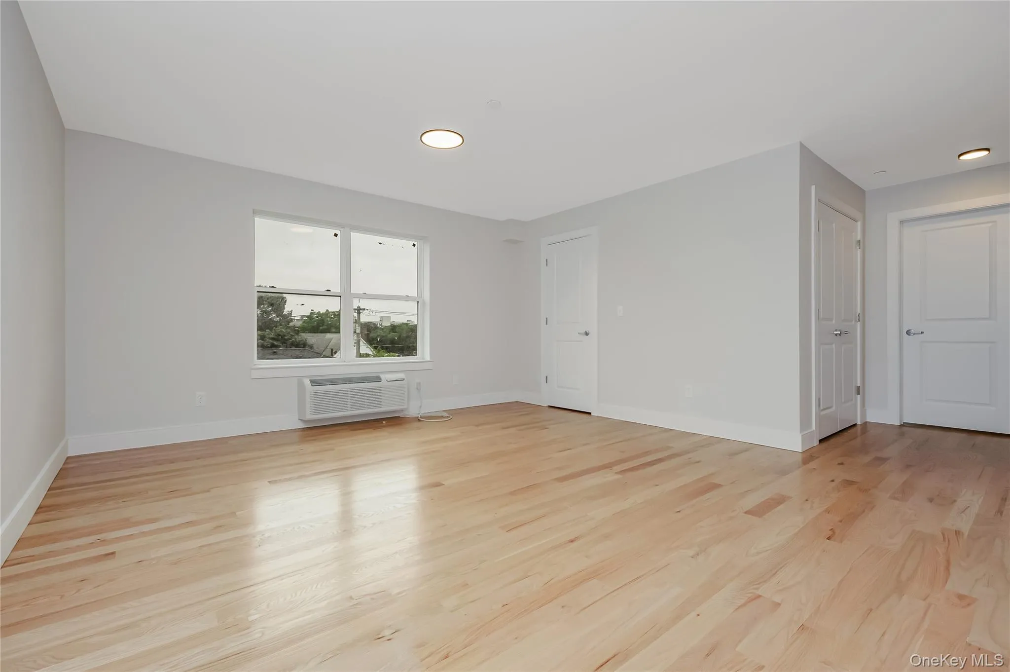 Spare room with light wood-style floors, a wall mounted air conditioner, and recessed lighting Spare room with light wood-style floors, a wall mounted air conditioner, and recessed lighting
