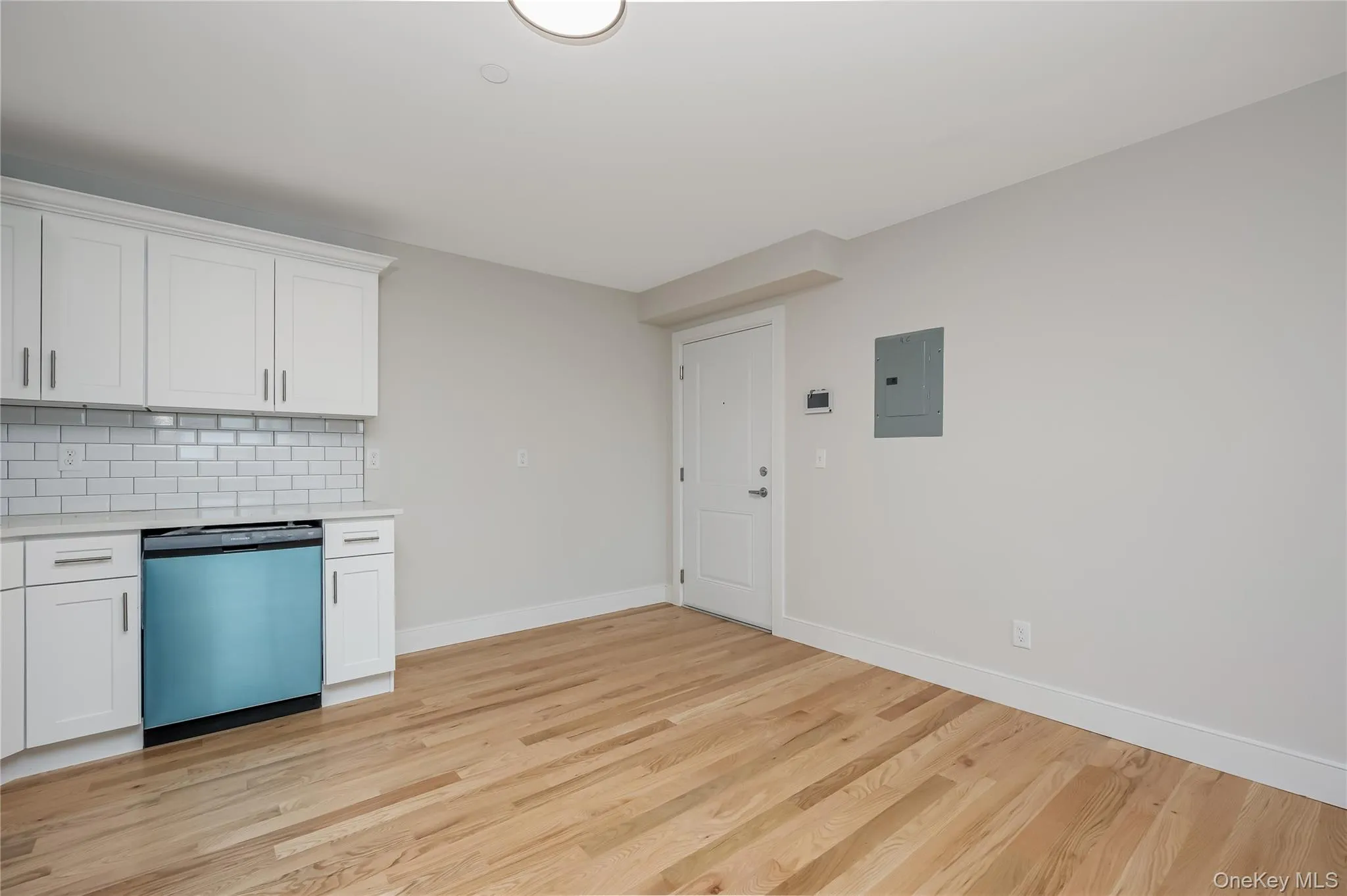 Kitchen with white cabinets, backsplash, dishwashing machine, and light wood-type flooring Kitchen with white cabinets, backsplash, dishwashing machine, and light wood-type flooring