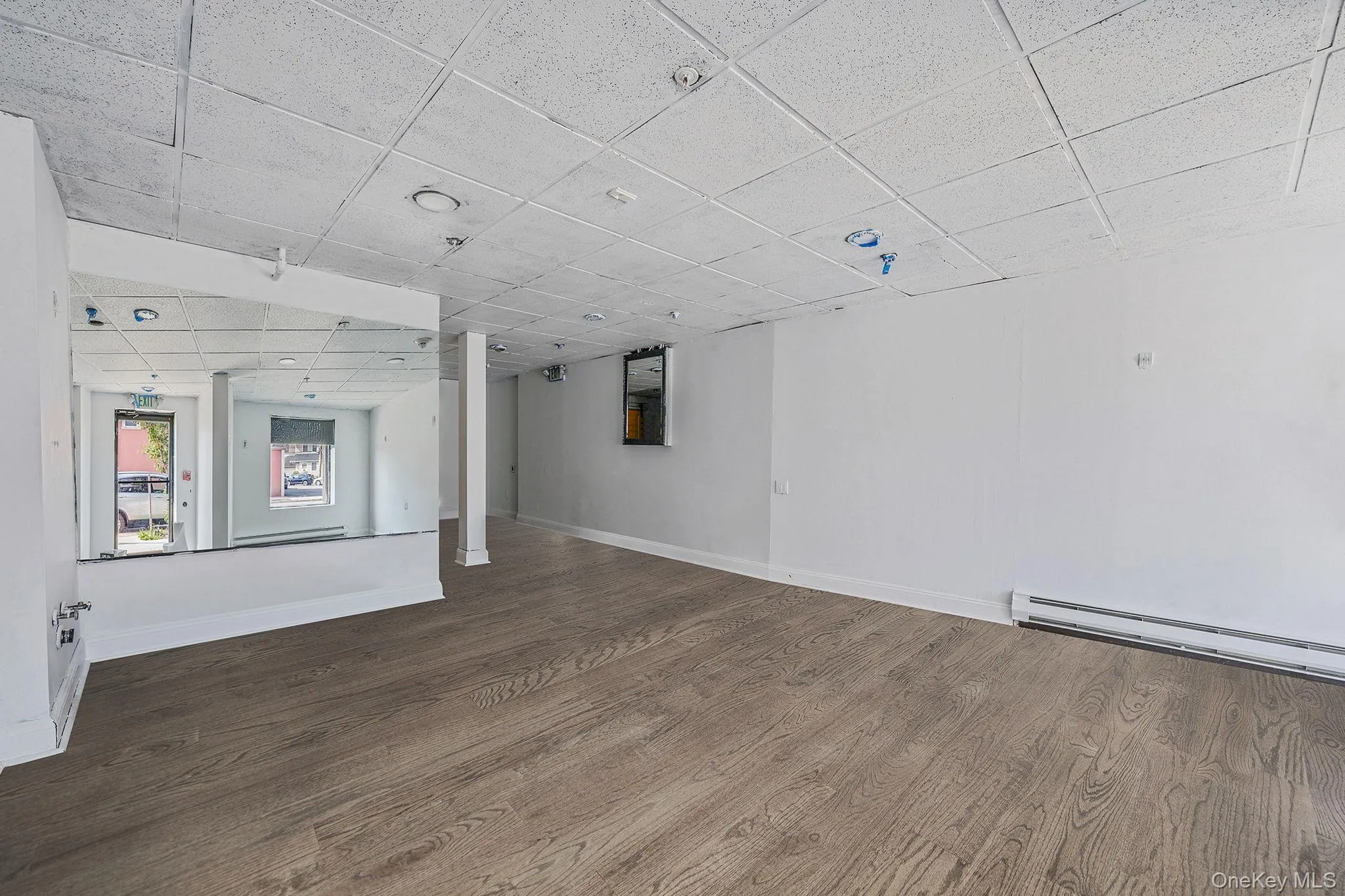 Basement featuring a drop ceiling, wood finished floors, and a baseboard heating unit Basement featuring a drop ceiling, wood finished floors, and a baseboard heating unit