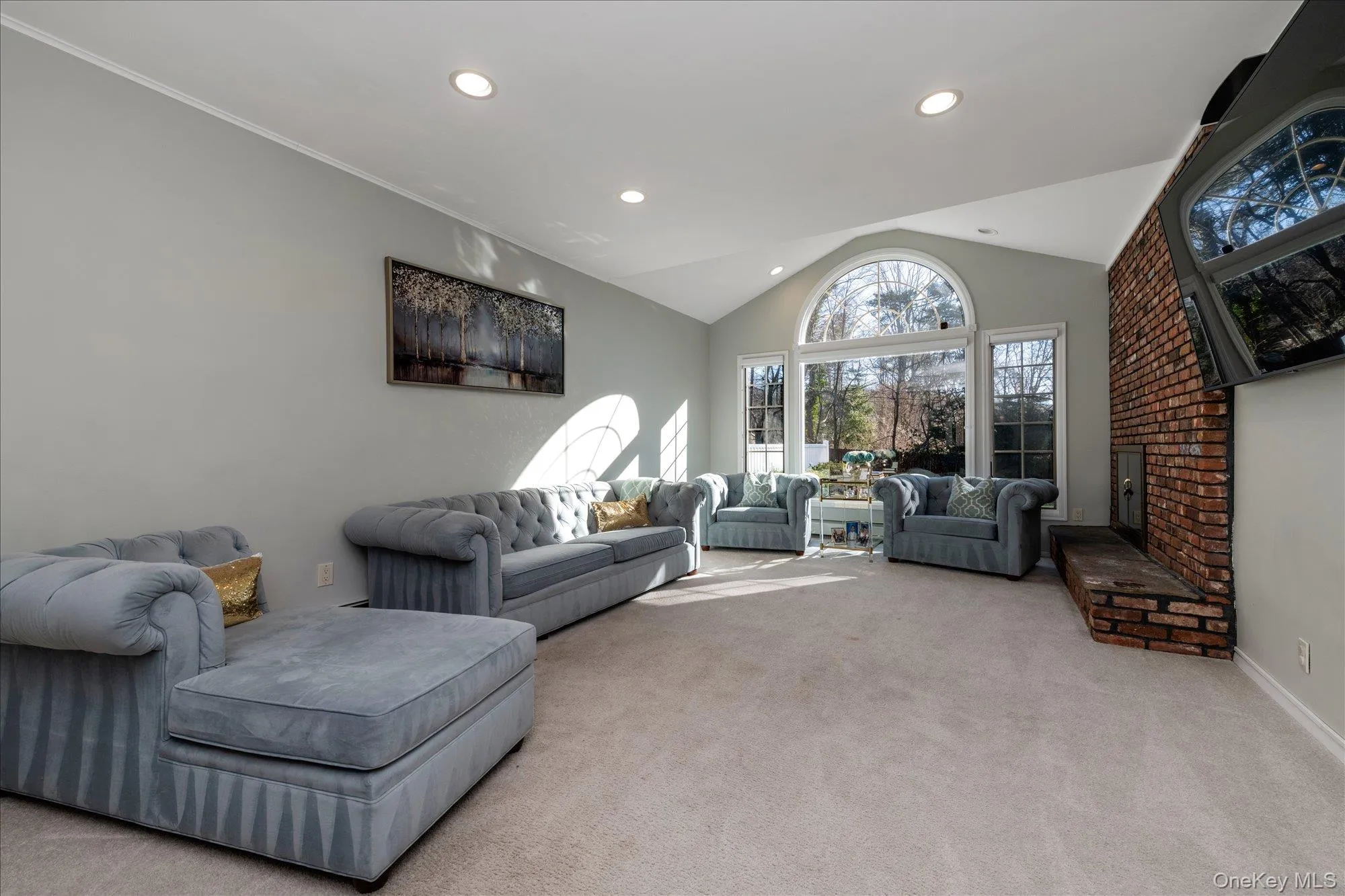 Living room featuring carpet, lofted ceiling, recessed lighting, and a brick fireplace Living room featuring carpet, lofted ceiling, recessed lighting, and a brick fireplace