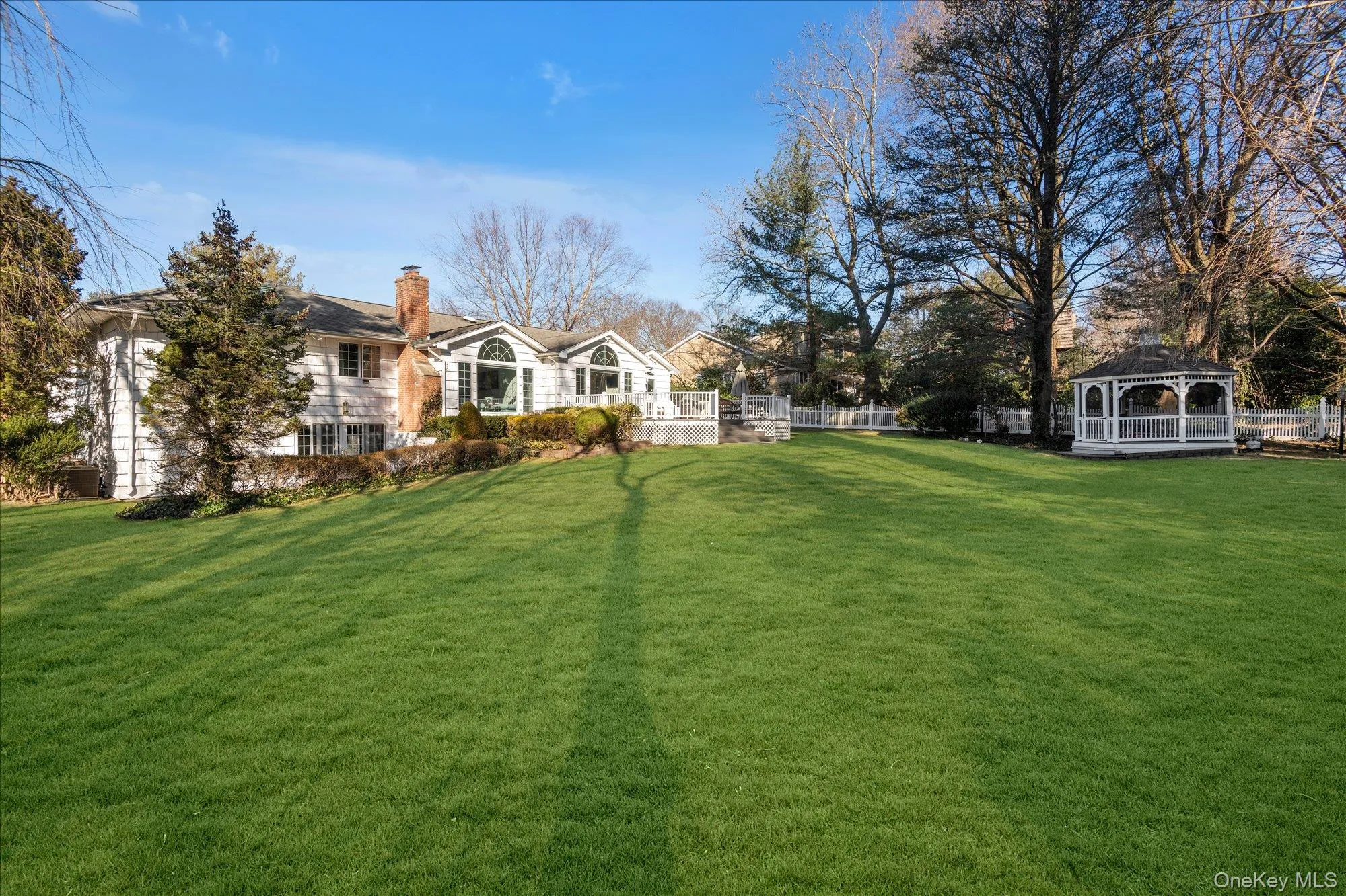 View of grassy yard with a gazebo and a wooden deck View of grassy yard with a gazebo and a wooden deck