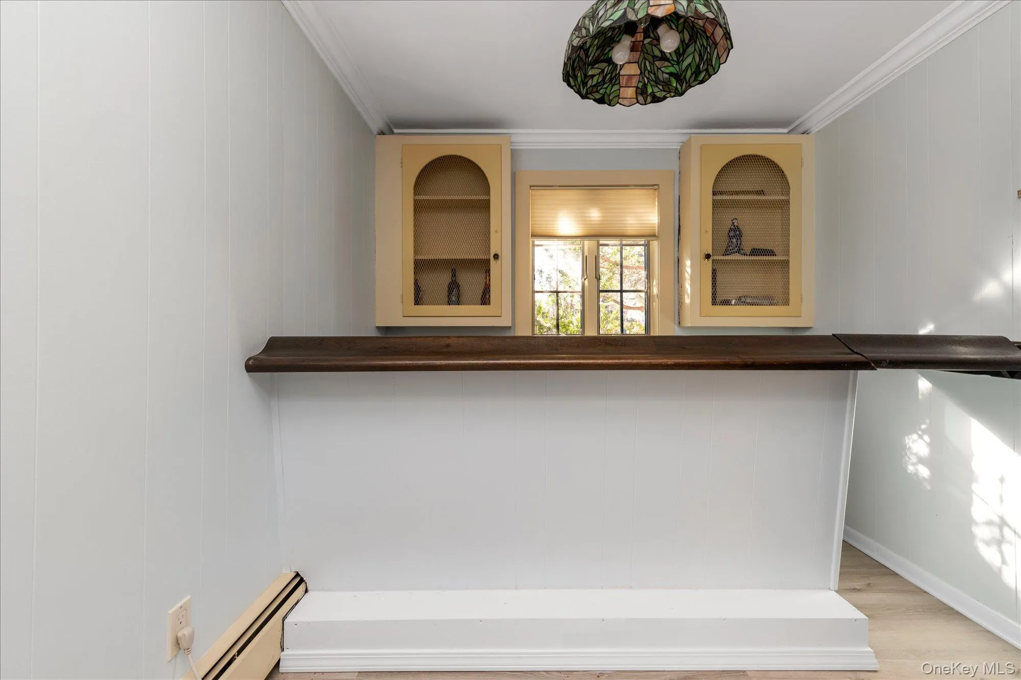 Bar area featuring ornamental molding, baseboard heating, wood counters, and light wood-style flooring Bar area featuring ornamental molding, baseboard heating, wood counters, and light wood-style flooring