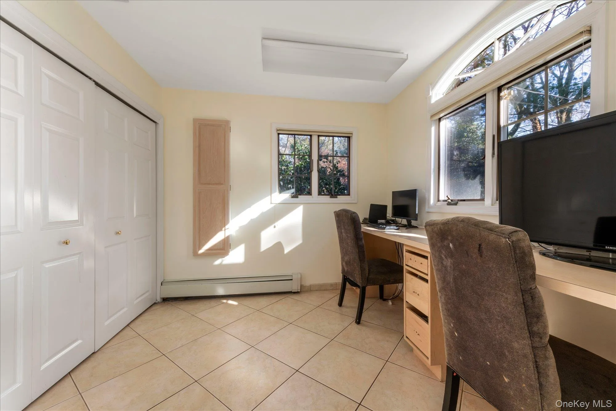 Home office with light tile patterned flooring and a baseboard heating unit Home office with light tile patterned flooring and a baseboard heating unit