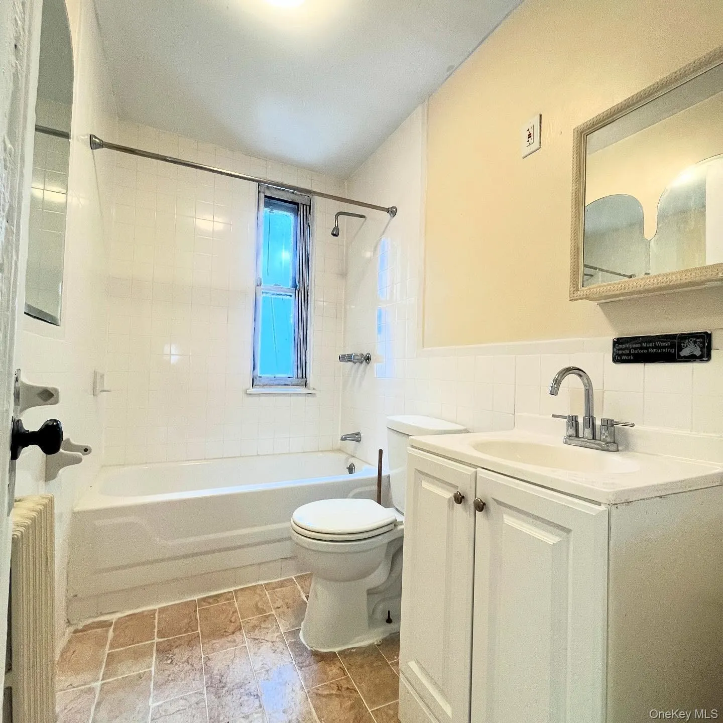 Bathroom featuring tub / shower combination, vanity, radiator heating unit, and tile walls Bathroom featuring tub / shower combination, vanity, radiator heating unit, and tile walls