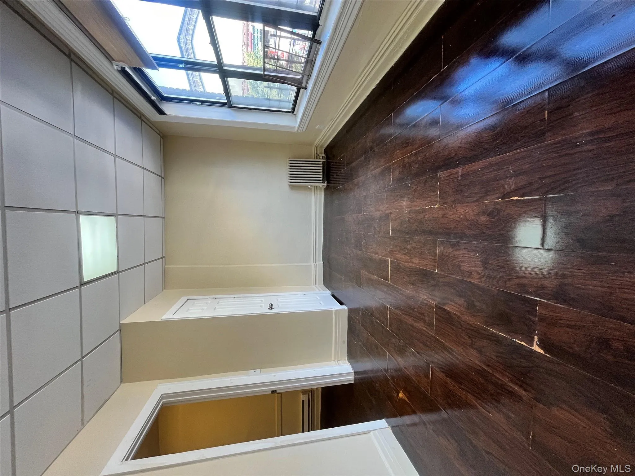 Empty room featuring dark wood-style floors, a drop ceiling, and radiator Empty room featuring dark wood-style floors, a drop ceiling, and radiator