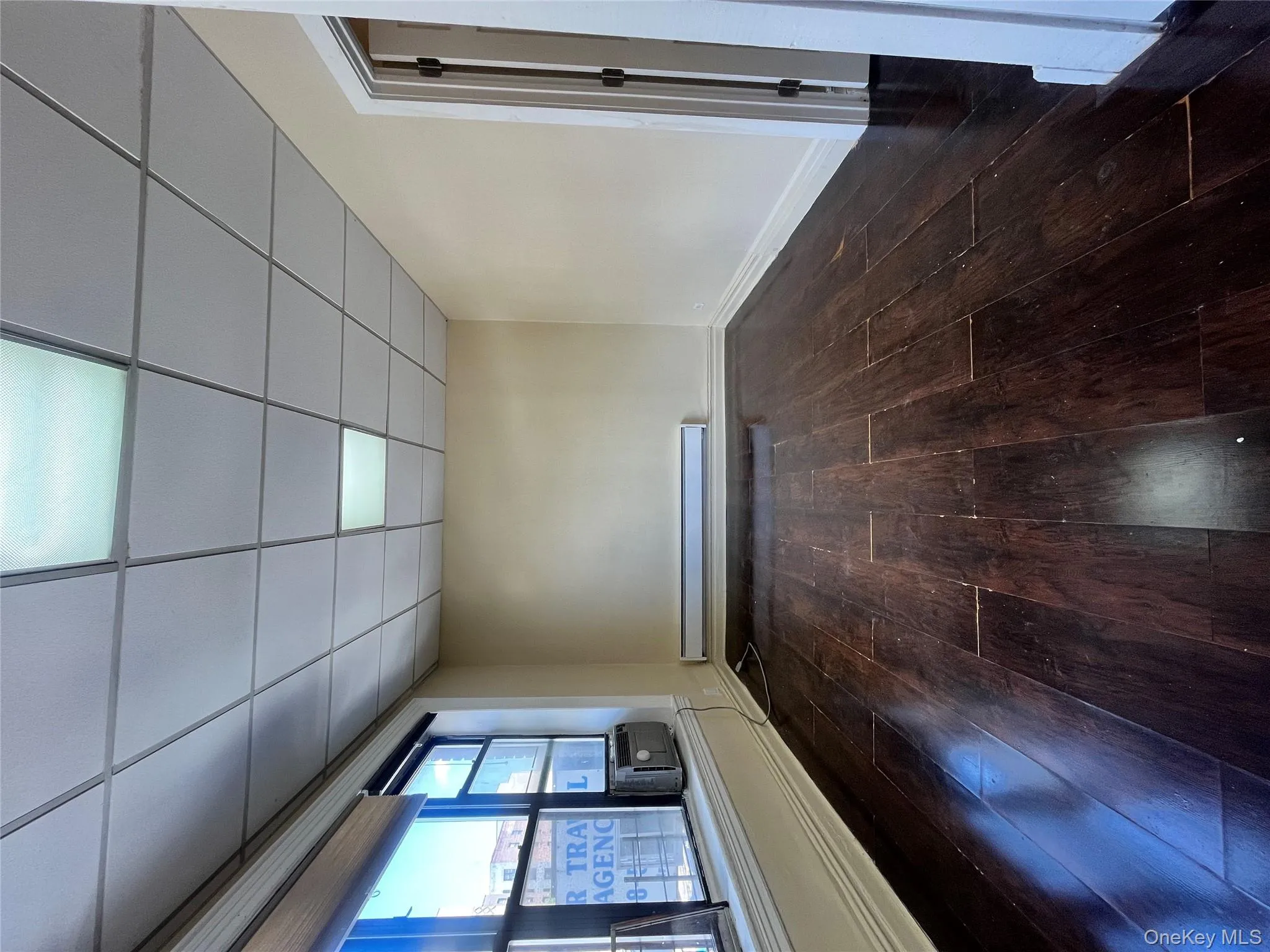 Empty room featuring dark wood finished floors, a drop ceiling, and a baseboard radiator Empty room featuring dark wood finished floors, a drop ceiling, and a baseboard radiator