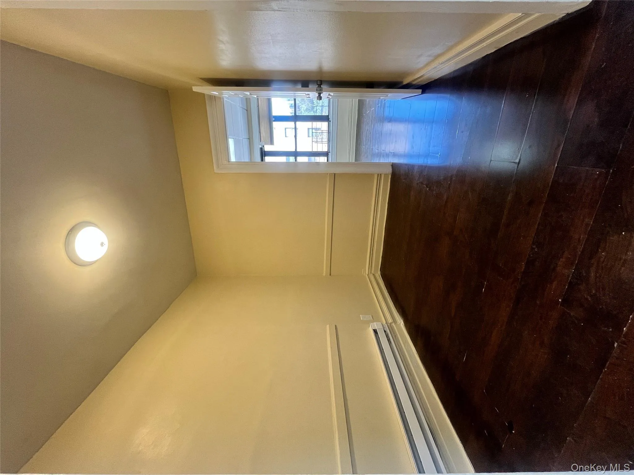 Unfurnished room with dark wood-style floors and a baseboard radiator Unfurnished room with dark wood-style floors and a baseboard radiator