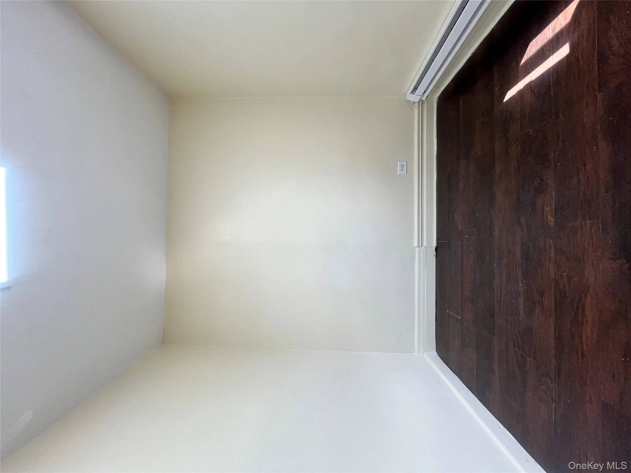 Empty room with dark wood-style flooring and baseboard heating Empty room with dark wood-style flooring and baseboard heating