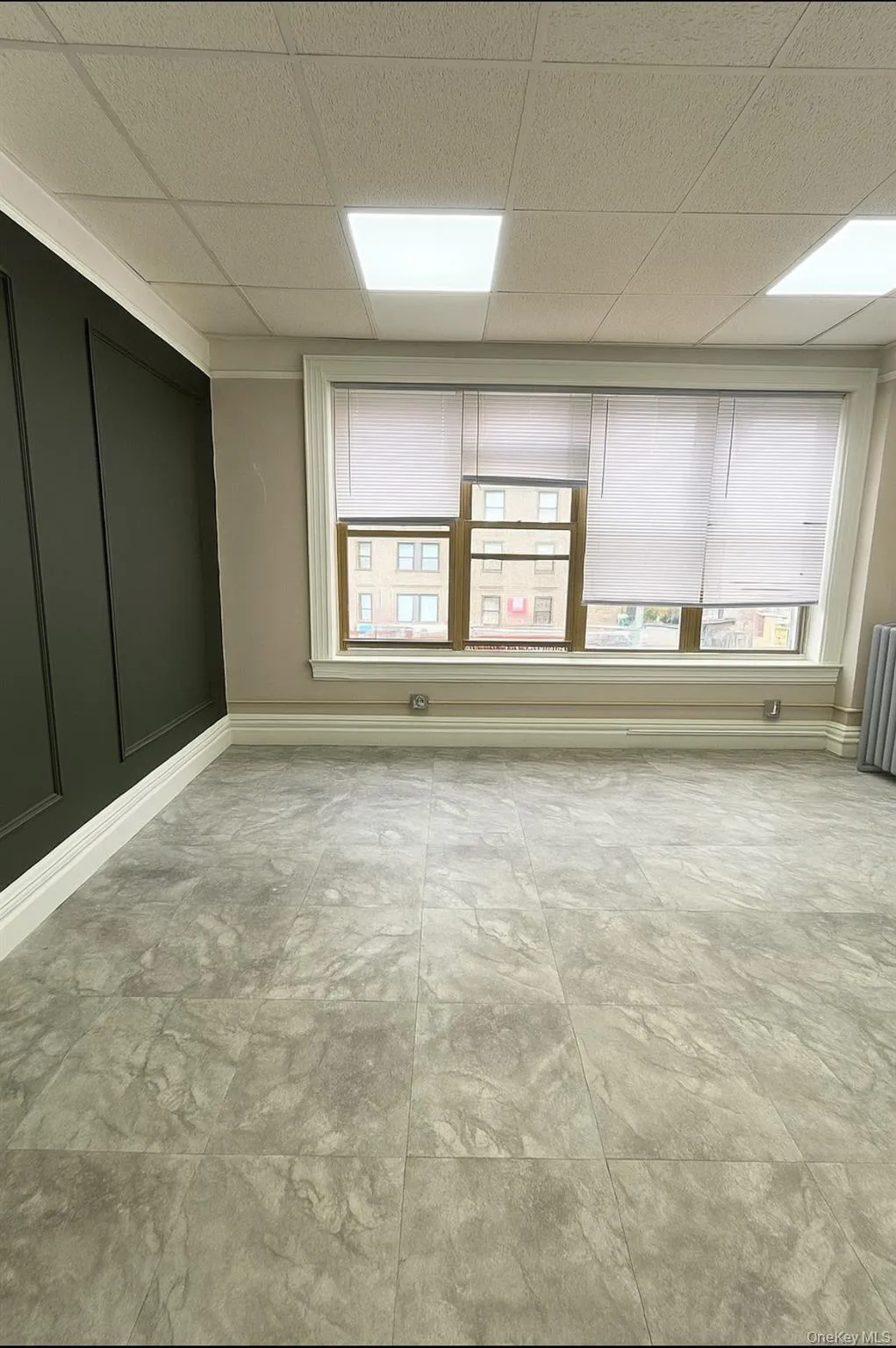 Unfurnished room with healthy amount of natural light, a drop ceiling, and a decorative wall Unfurnished room with healthy amount of natural light, a drop ceiling, and a decorative wall