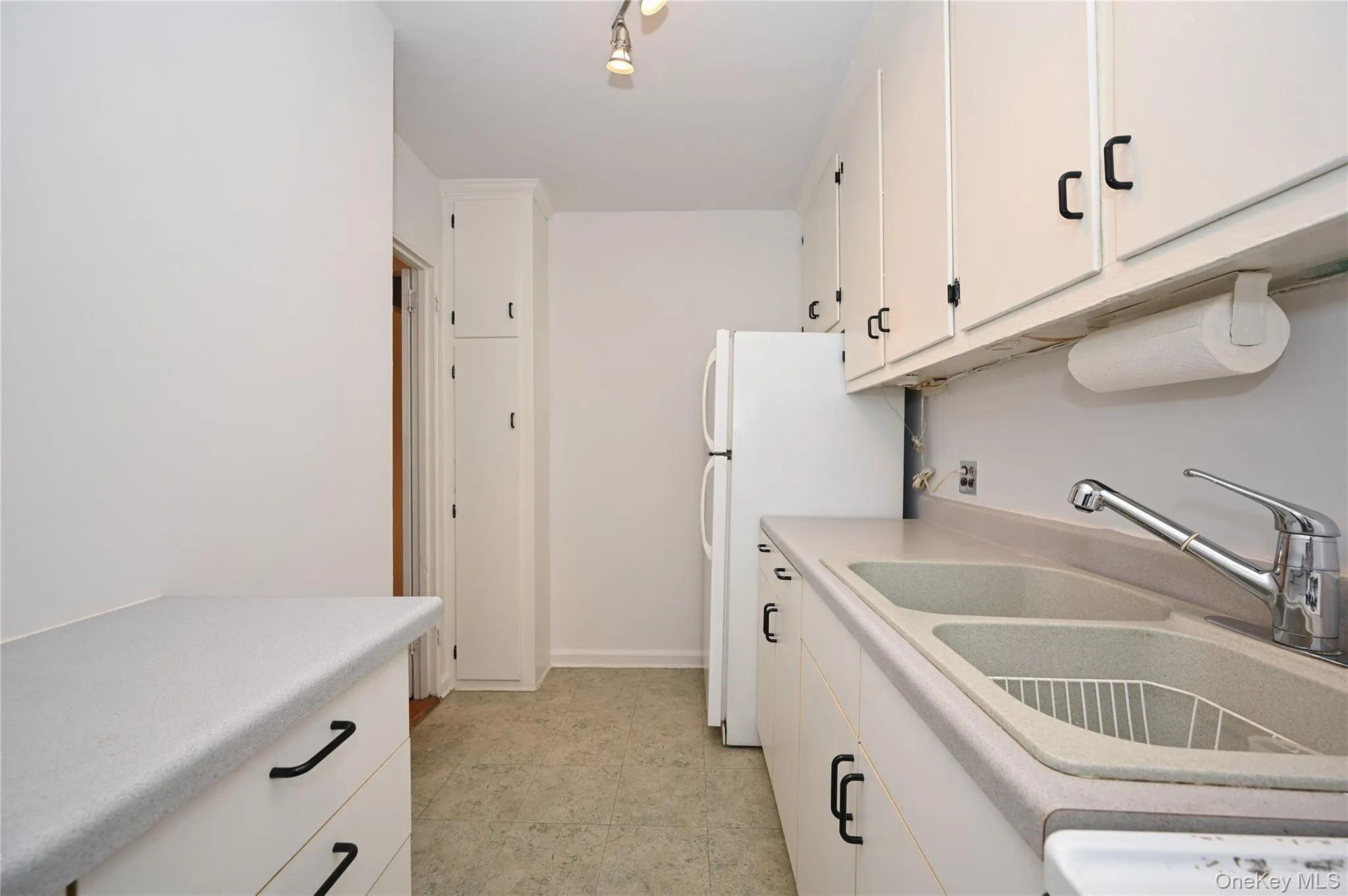 Kitchen featuring white cabinets, light countertops, and freestanding refrigerator Kitchen featuring white cabinets, light countertops, and freestanding refrigerator