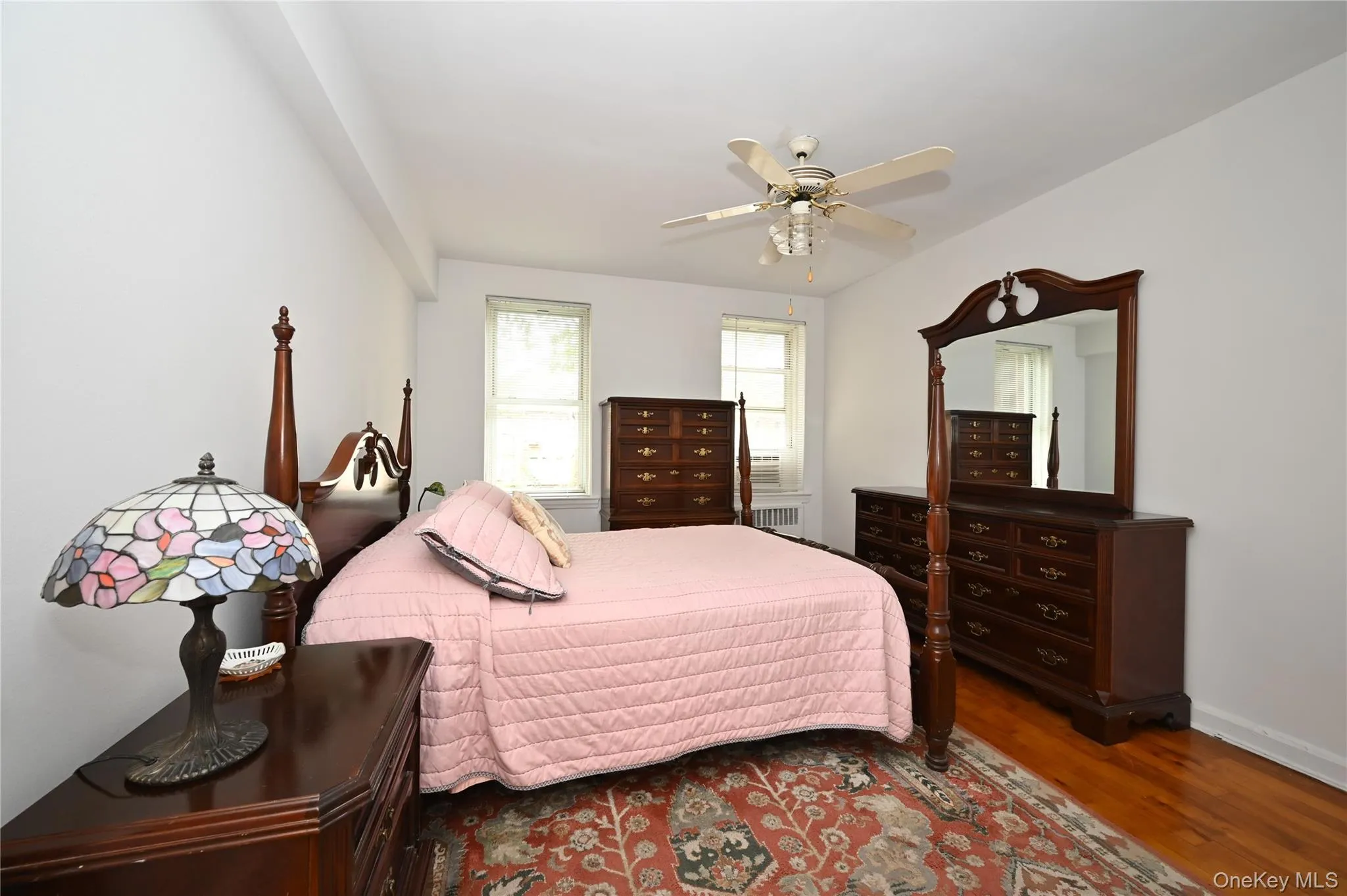 Bedroom featuring wood finished floors, a ceiling fan, and radiator heating unit Bedroom featuring wood finished floors, a ceiling fan, and radiator heating unit