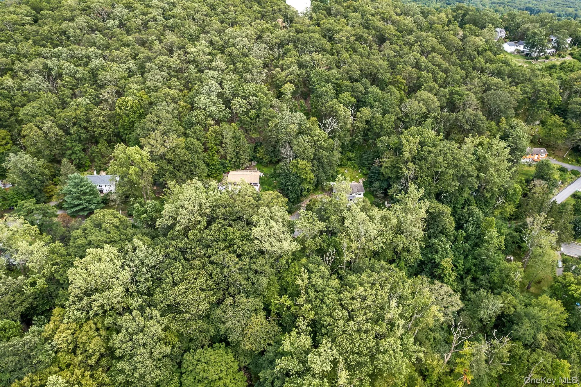 Aerial view of property and surrounding area featuring a heavily wooded area Aerial view of property and surrounding area featuring a heavily wooded area
