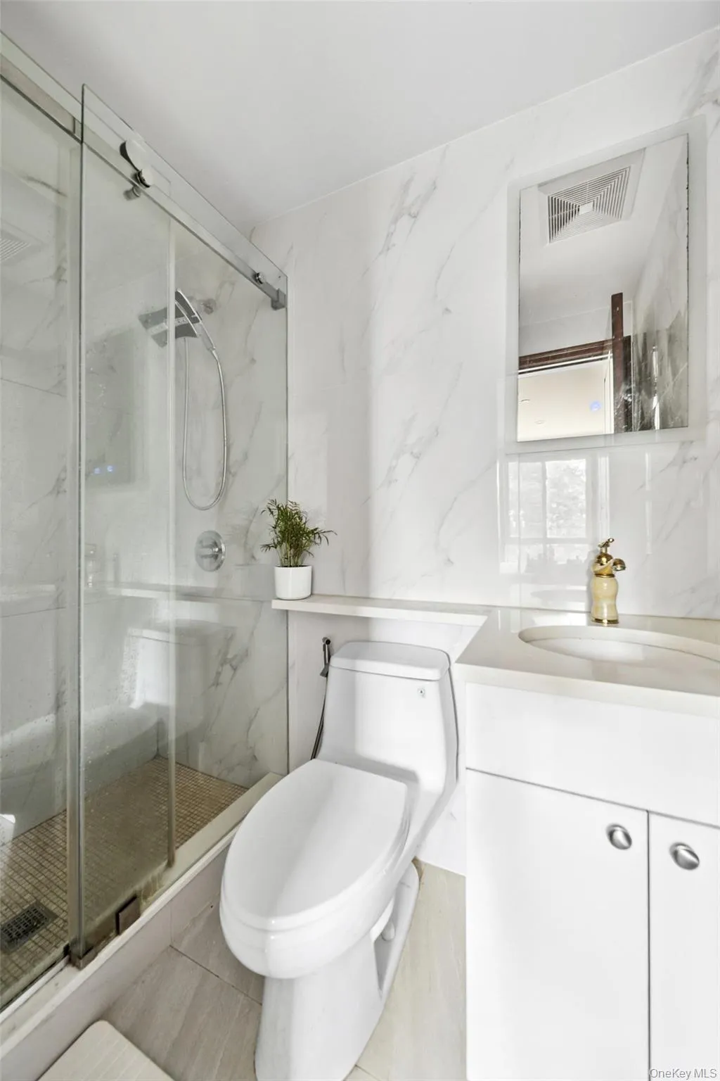 Bathroom with vanity, a marble finish shower, light tile patterned floors, and tile walls Bathroom with vanity, a marble finish shower, light tile patterned floors, and tile walls