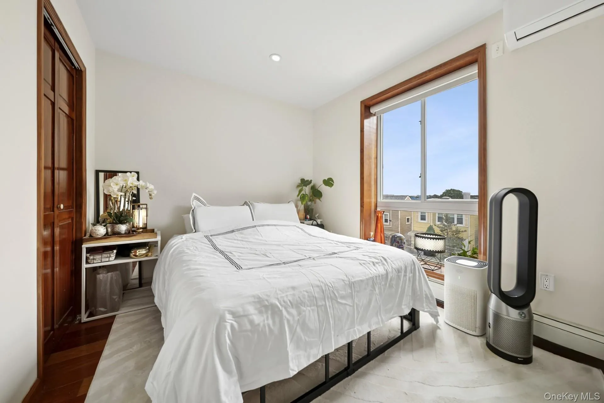 Bedroom featuring an AC wall unit, light wood-style flooring, a closet, a baseboard radiator, and recessed lighting Bedroom featuring an AC wall unit, light wood-style flooring, a closet, a baseboard radiator, and recessed lighting