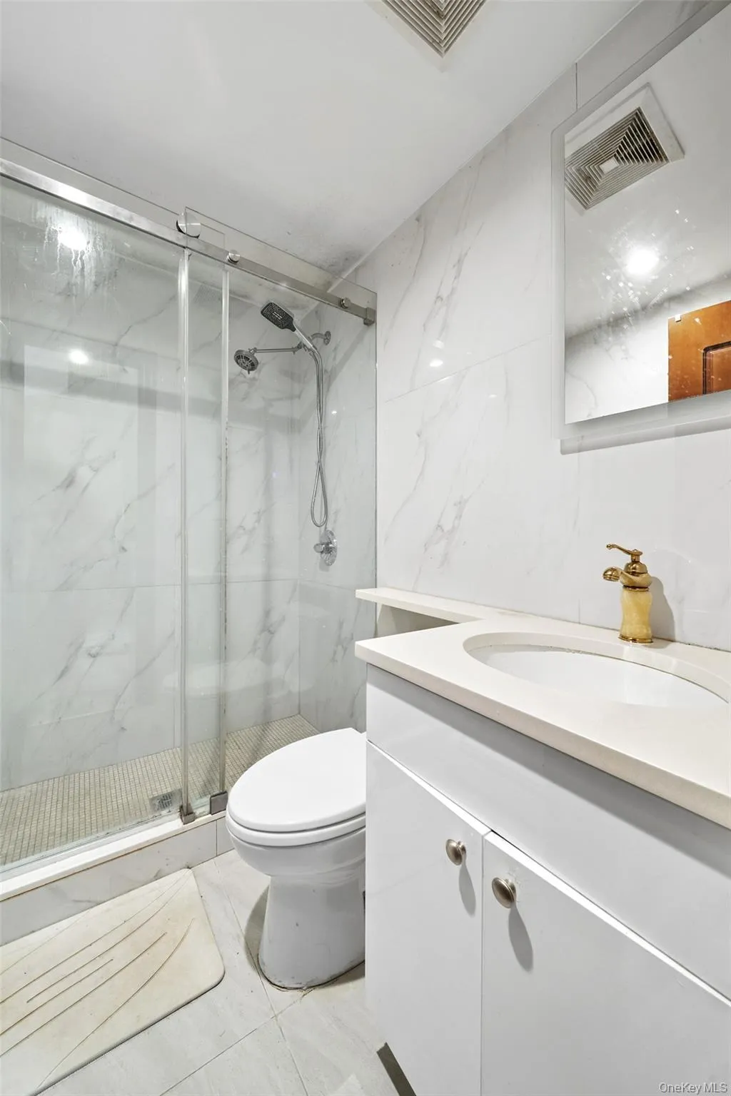 Full bath featuring vanity, a marble finish shower, and tile walls Full bath featuring vanity, a marble finish shower, and tile walls