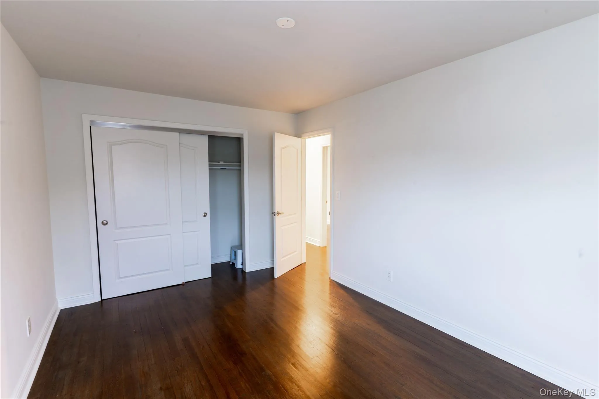 Unfurnished bedroom featuring dark wood-style floors and a closet Unfurnished bedroom featuring dark wood-style floors and a closet