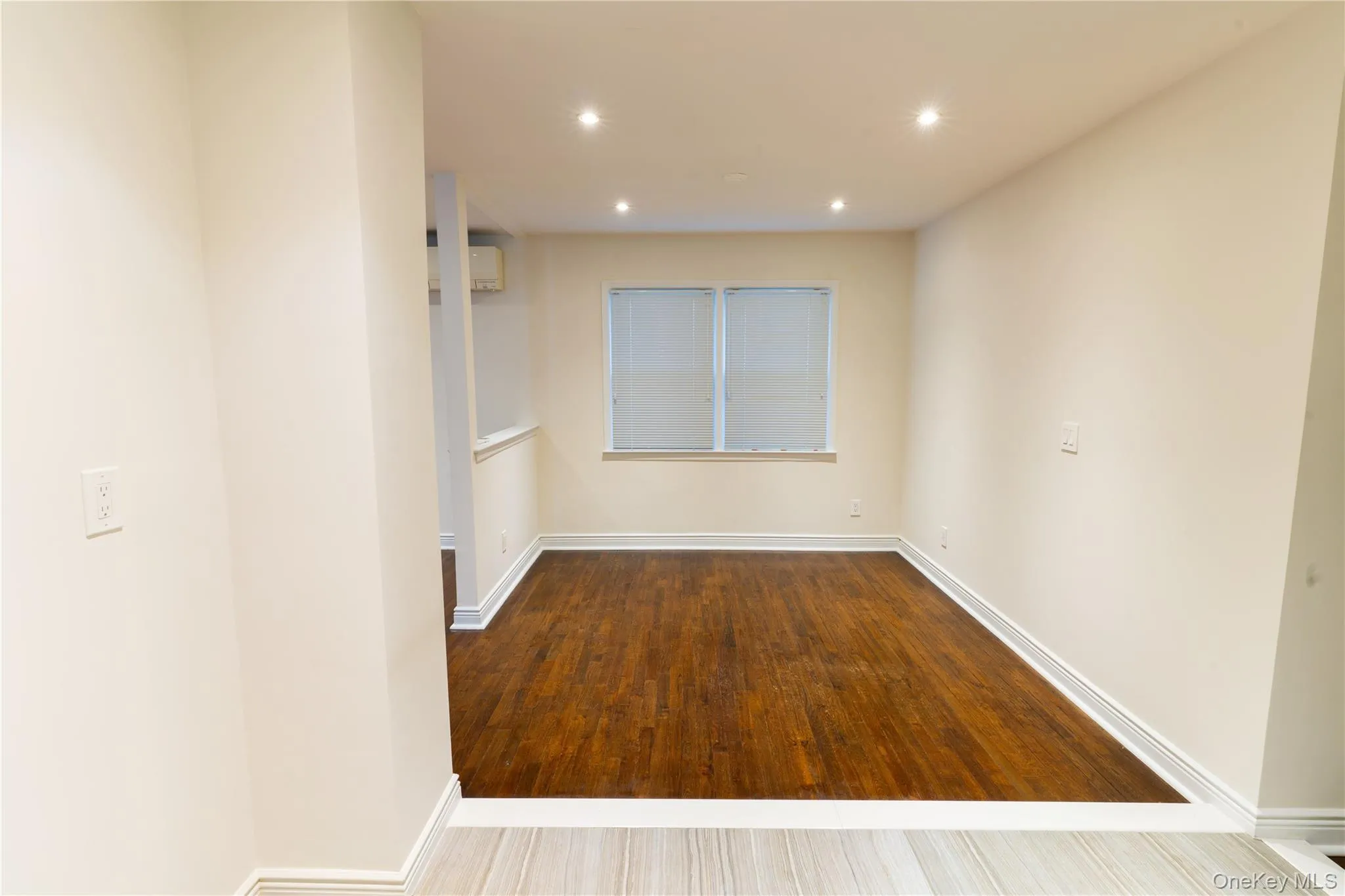 Empty room with recessed lighting, wood finished floors, and an AC wall unit Empty room with recessed lighting, wood finished floors, and an AC wall unit