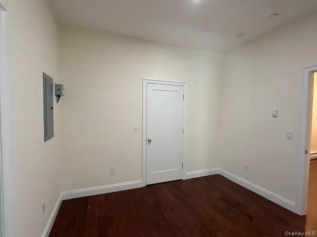 Unfurnished room with dark wood-type flooring and electric panel Unfurnished room with dark wood-type flooring and electric panel
