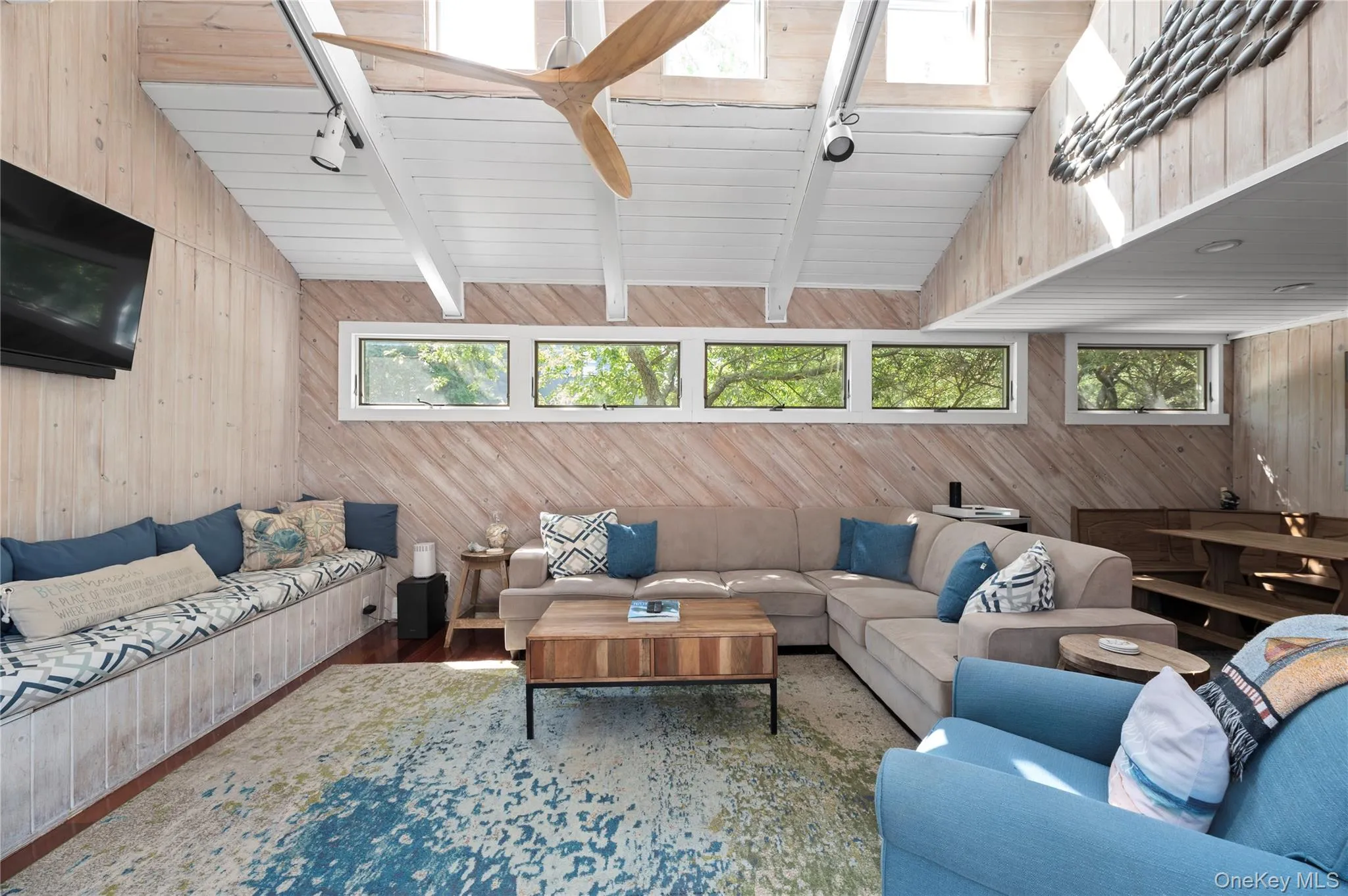 Living area featuring wooden walls, healthy amount of natural light, wood finished floors, track lighting, and wooden ceiling Living area featuring wooden walls, healthy amount of natural light, wood finished floors, track lighting, and wooden ceiling