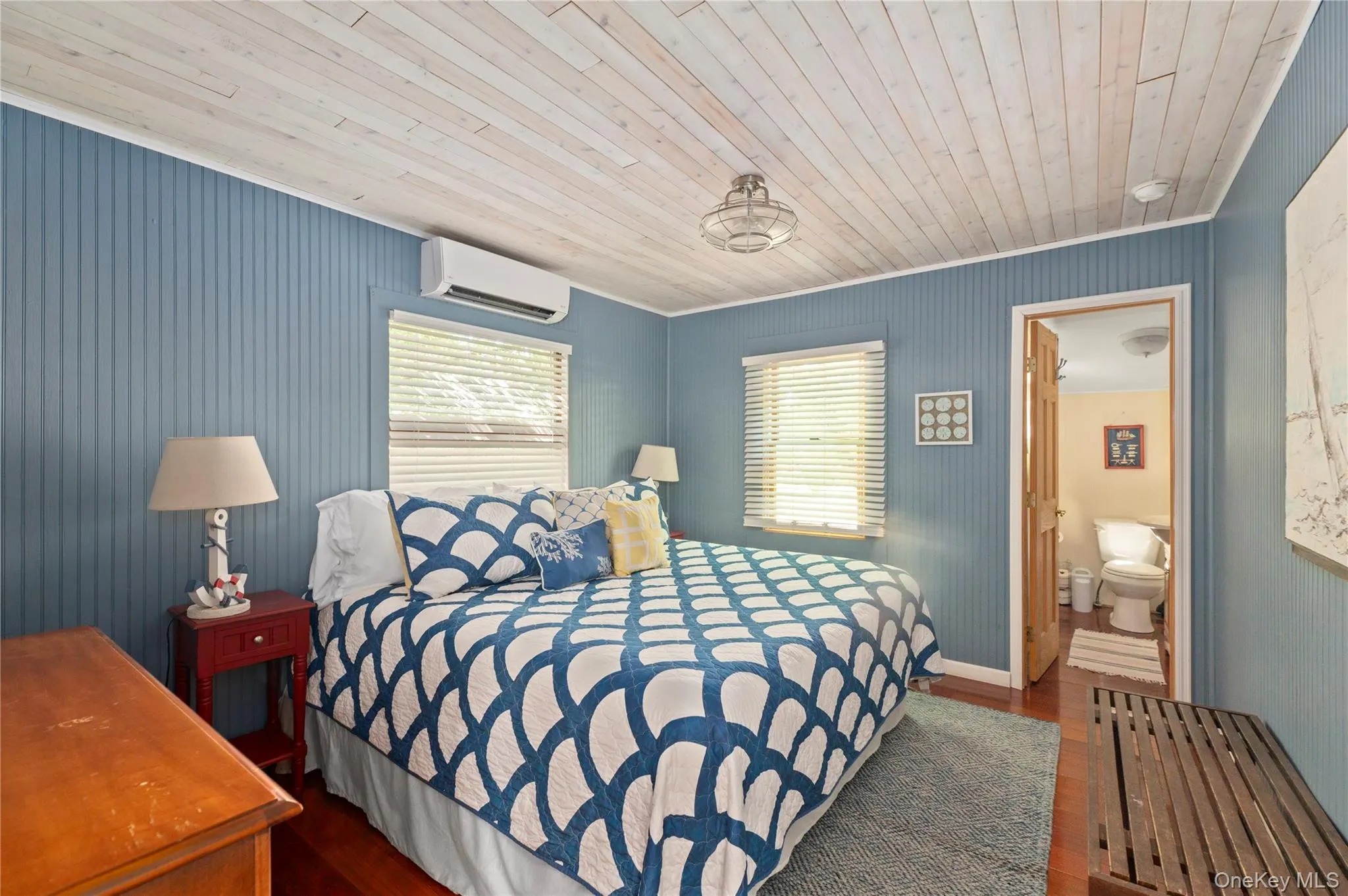 Bedroom with dark wood-type flooring, wood ceiling, ensuite bath, and a wall mounted AC Bedroom with dark wood-type flooring, wood ceiling, ensuite bath, and a wall mounted AC