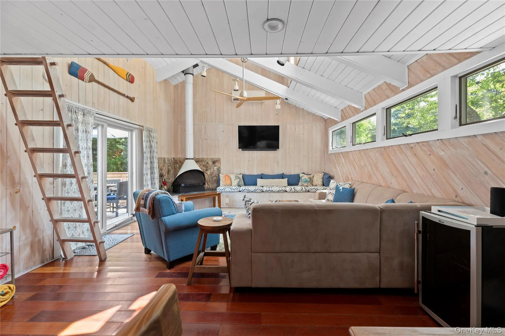 Living area with wood walls, healthy amount of natural light, hardwood / wood-style floors, a wooden ceiling with exposed beams, and stairway Living area with wood walls, healthy amount of natural light, hardwood / wood-style floors, a wooden ceiling with exposed beams, and stairway