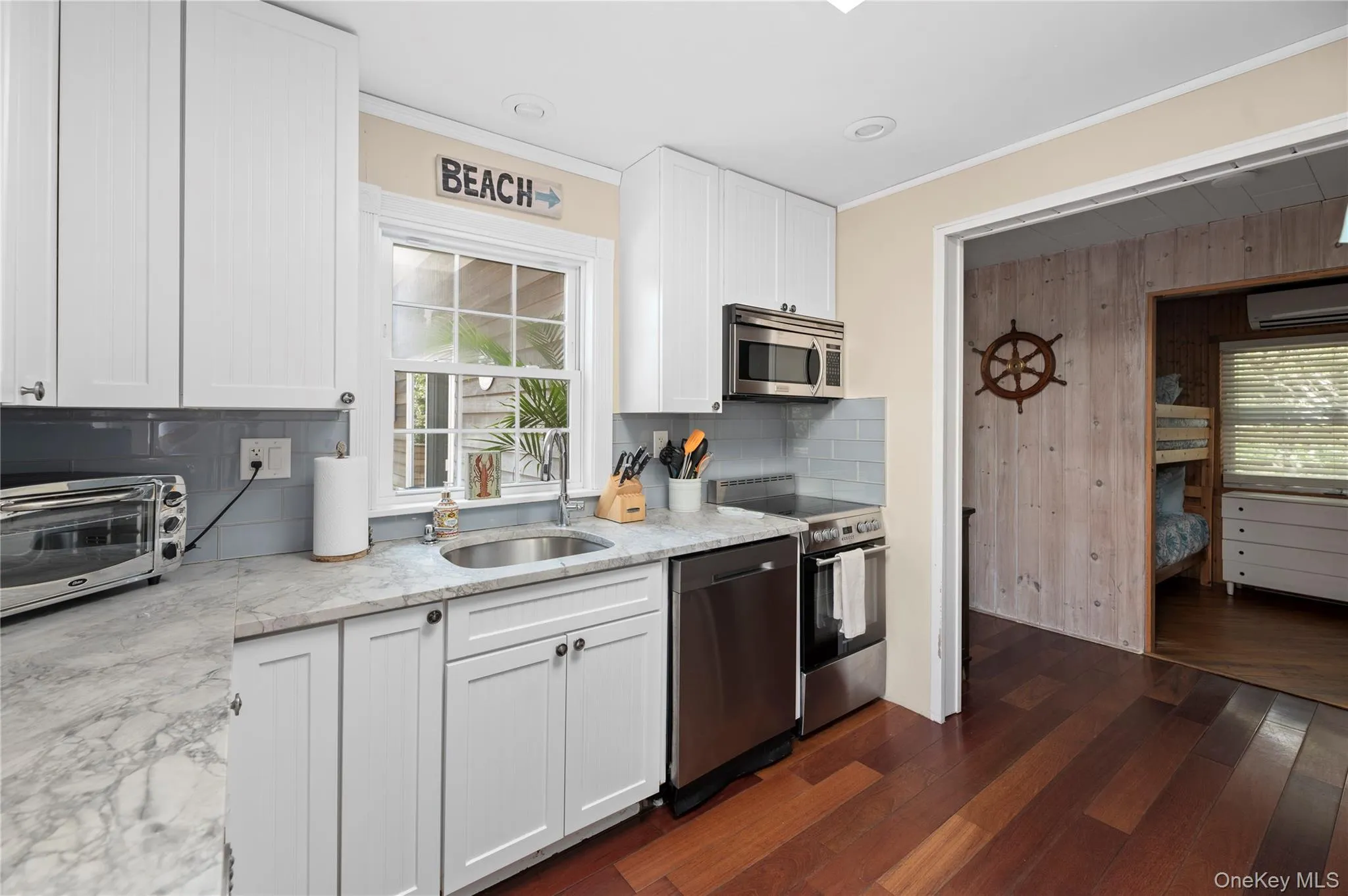 Kitchen with white cabinets, appliances with stainless steel finishes, light stone countertops, backsplash, and ornamental molding Kitchen with white cabinets, appliances with stainless steel finishes, light stone countertops, backsplash, and ornamental molding